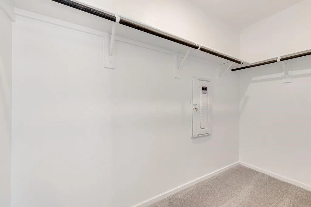 Spacious closet with electric panel and light carpet