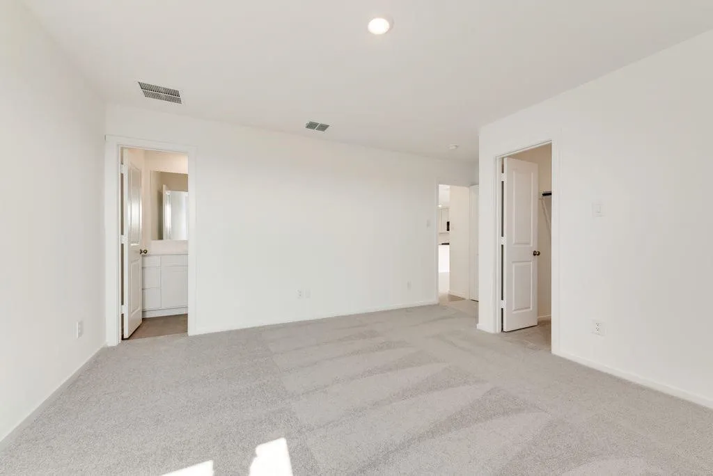 Unfurnished bedroom featuring light carpet and connected bathroom