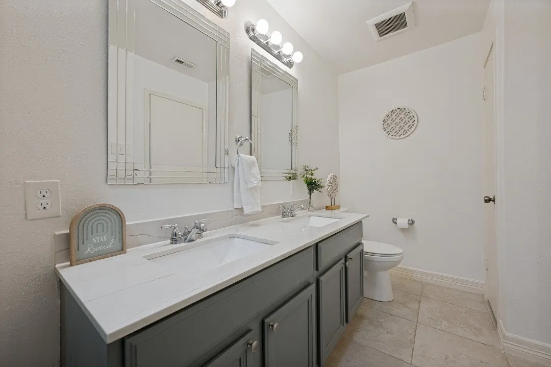 Dual vanity with integrated sinks, white countertops, and gray cabinetry