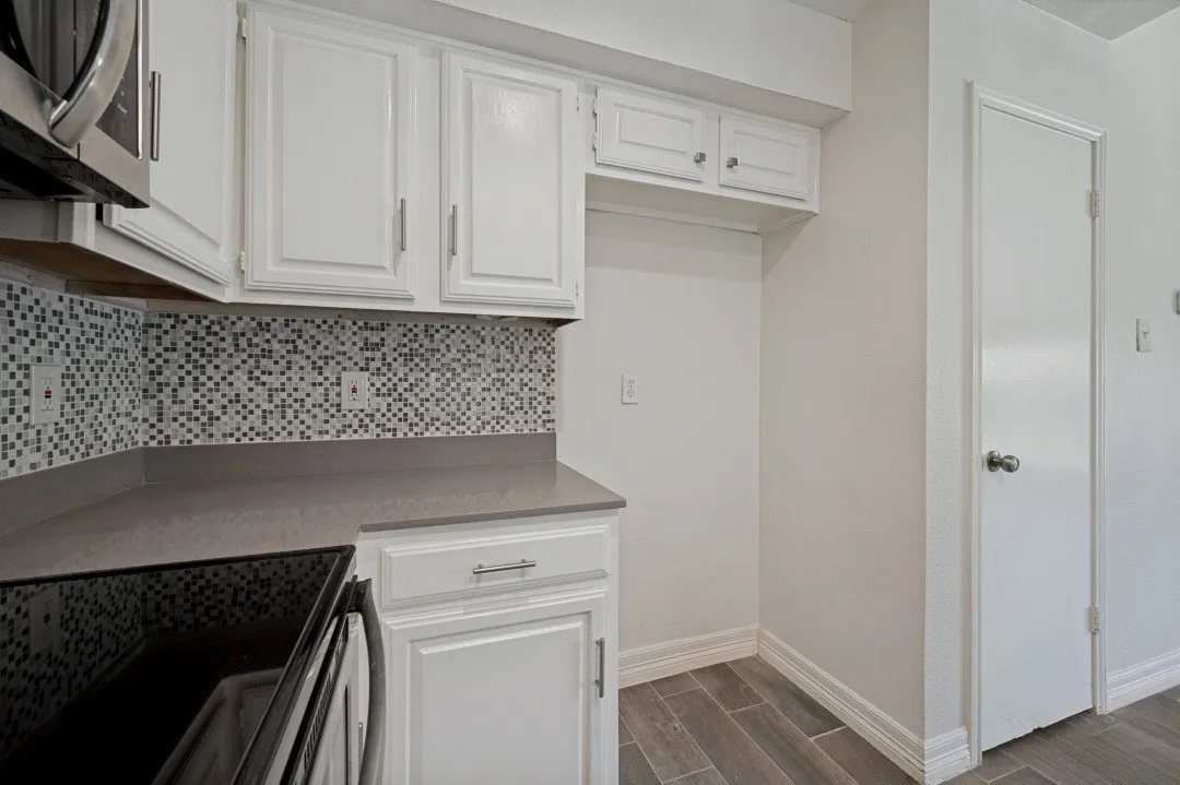 Kitchen featuring white cabinetry, grey countertops, mosaic tile backsplash, black cooktop, and wood-finish flooring