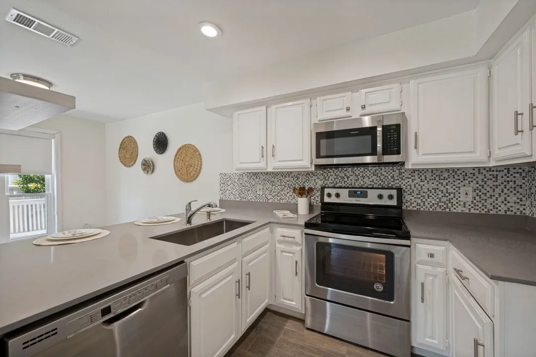 Modern kitchen featuring white cabinetry, stainless steel appliances, a mosaic tile backsplash, and a large single-basin sink