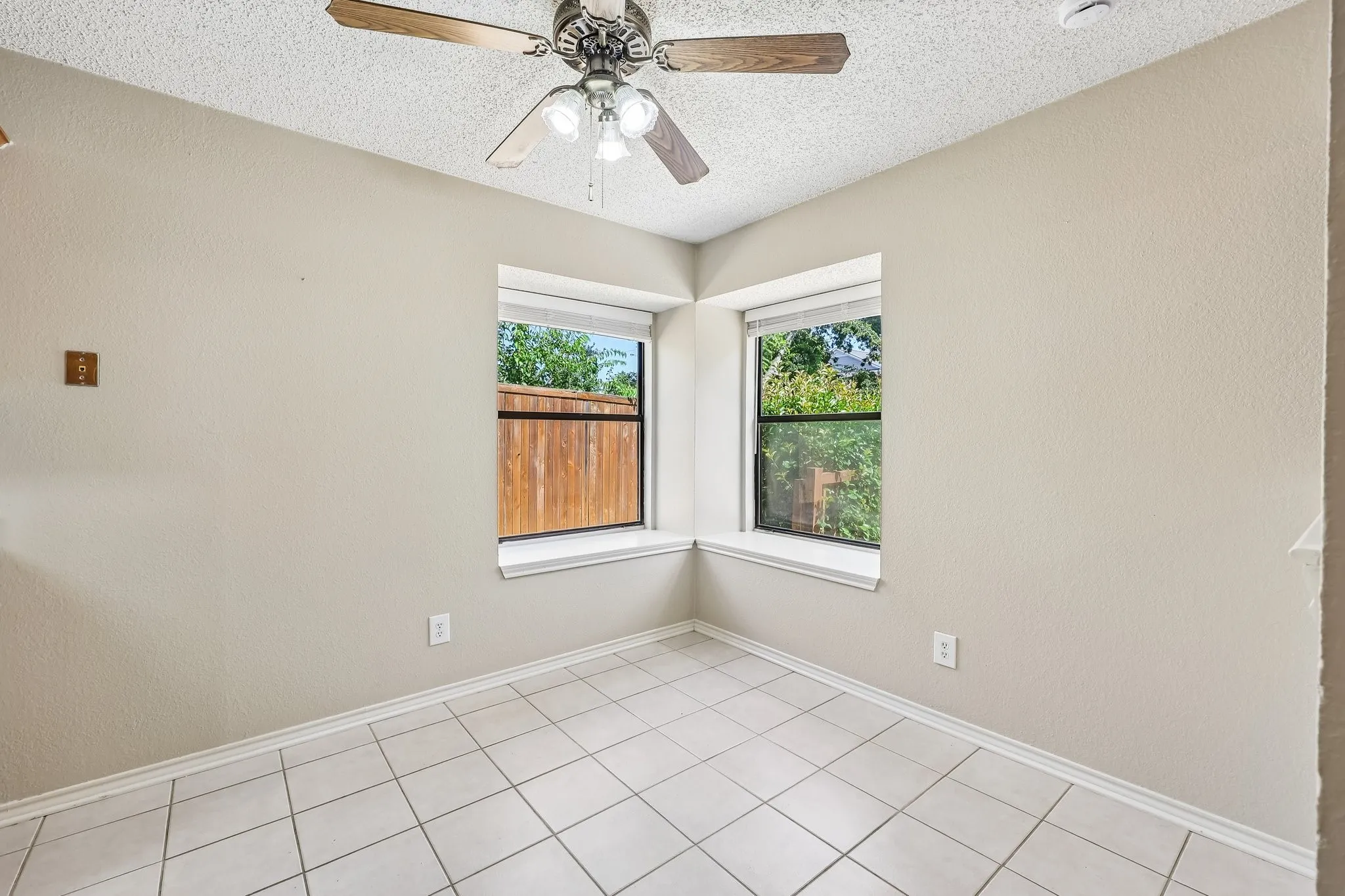 Room featuring square tile flooring, neutral wall tones, and a ceiling fan with integrated lighting