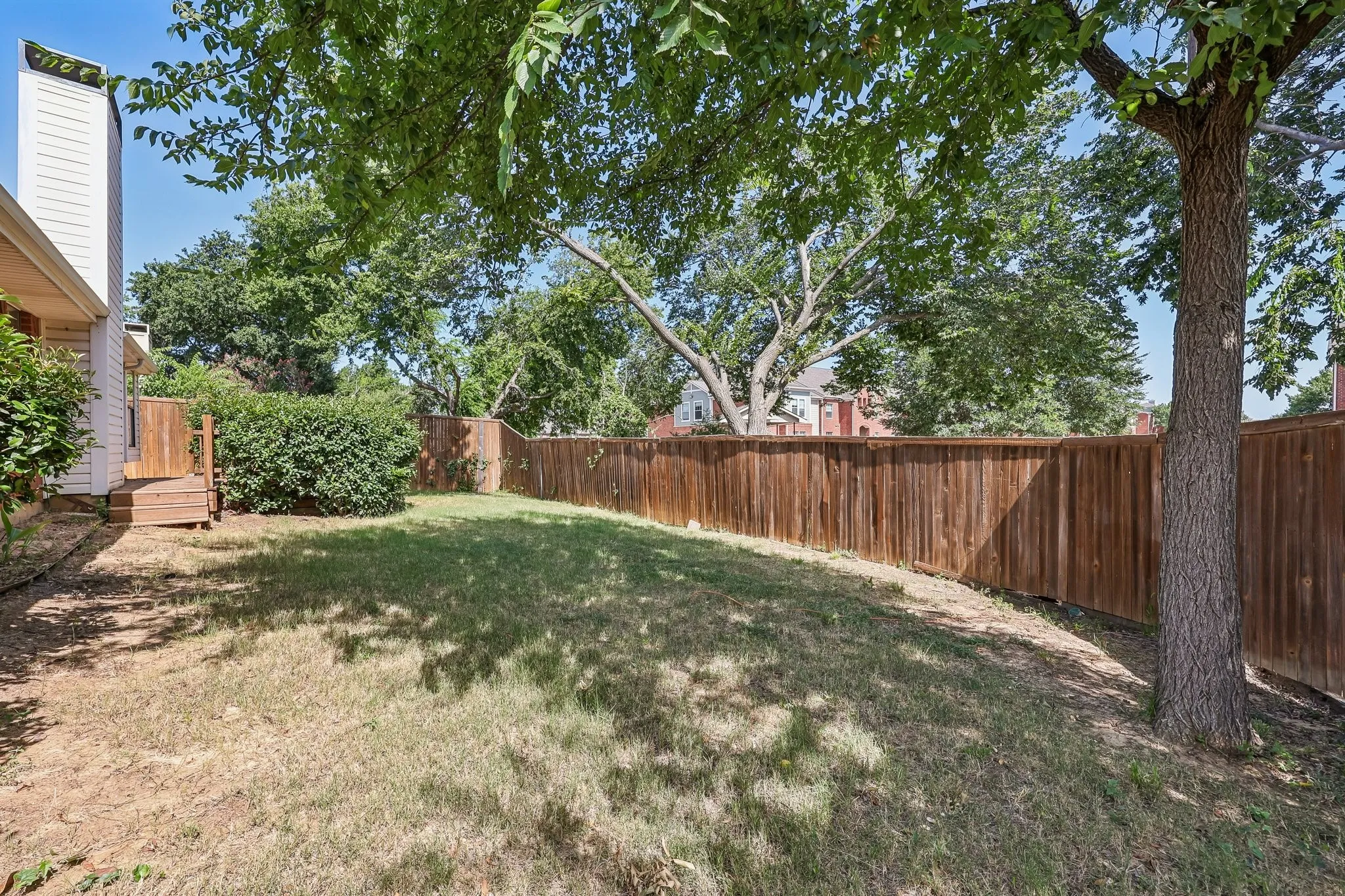 Private backyard featuring a wood privacy fence, established trees, and a small wooden deck structure