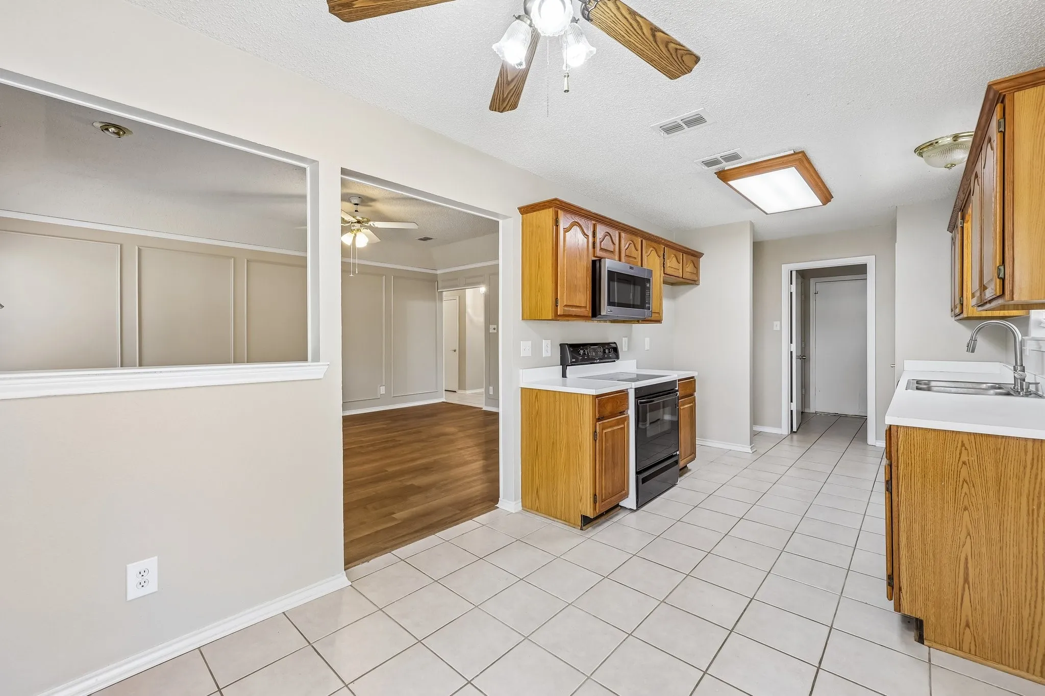 Kitchen featuring tile flooring, wood-finish cabinetry, white countertops, built-in microwave, and electric range