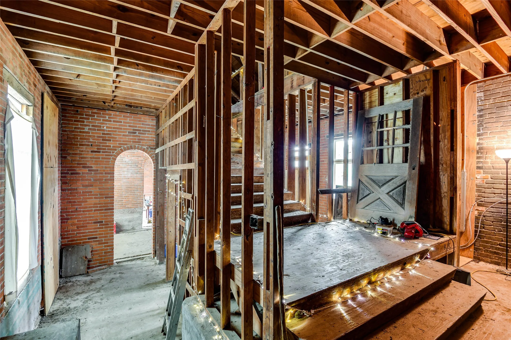 Miscellaneous room featuring arched walkways, brick wall, and a wealth of natural light