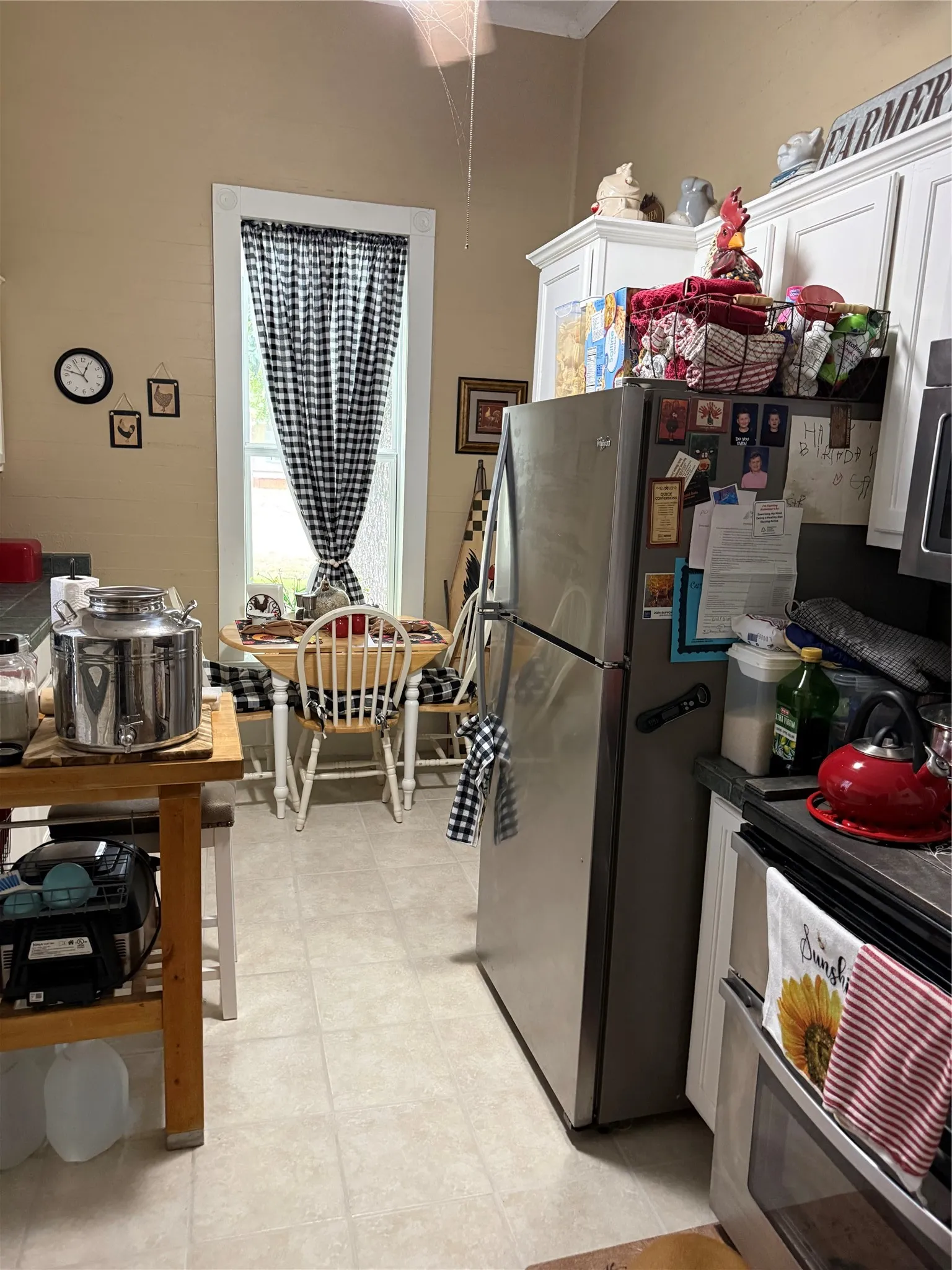 Kitchen featuring neutral-toned walls, white cabinetry, a window with trim, light-colored flooring, and built-in appliances