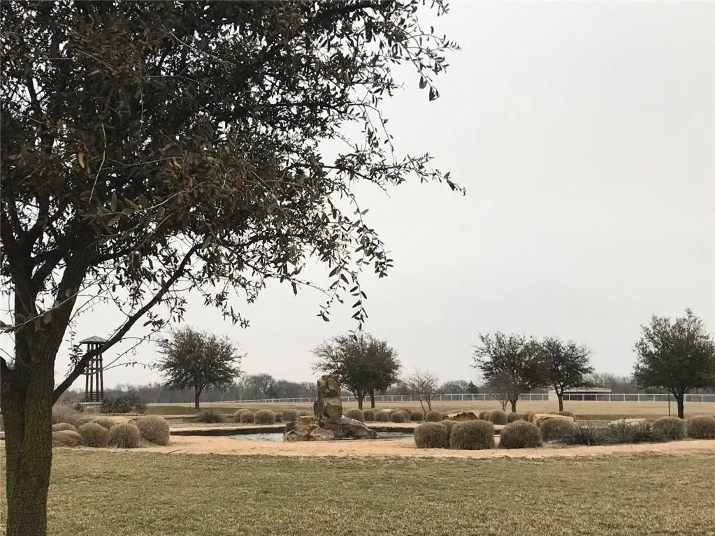 Expansive grounds featuring a circular hardscaped area with a central water feature, surrounded by low-growing shrubs