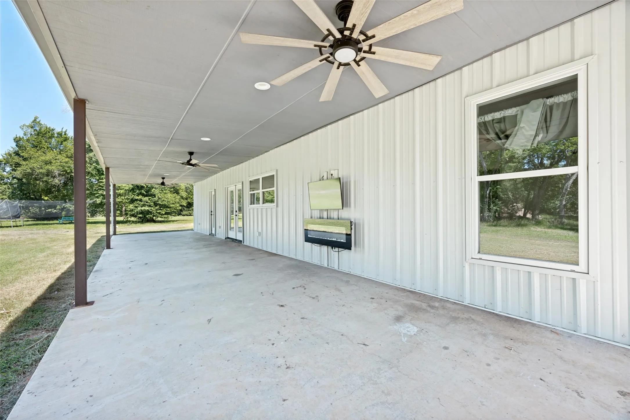 Expansive covered patio featuring a concrete surface and a white metal exterior wall