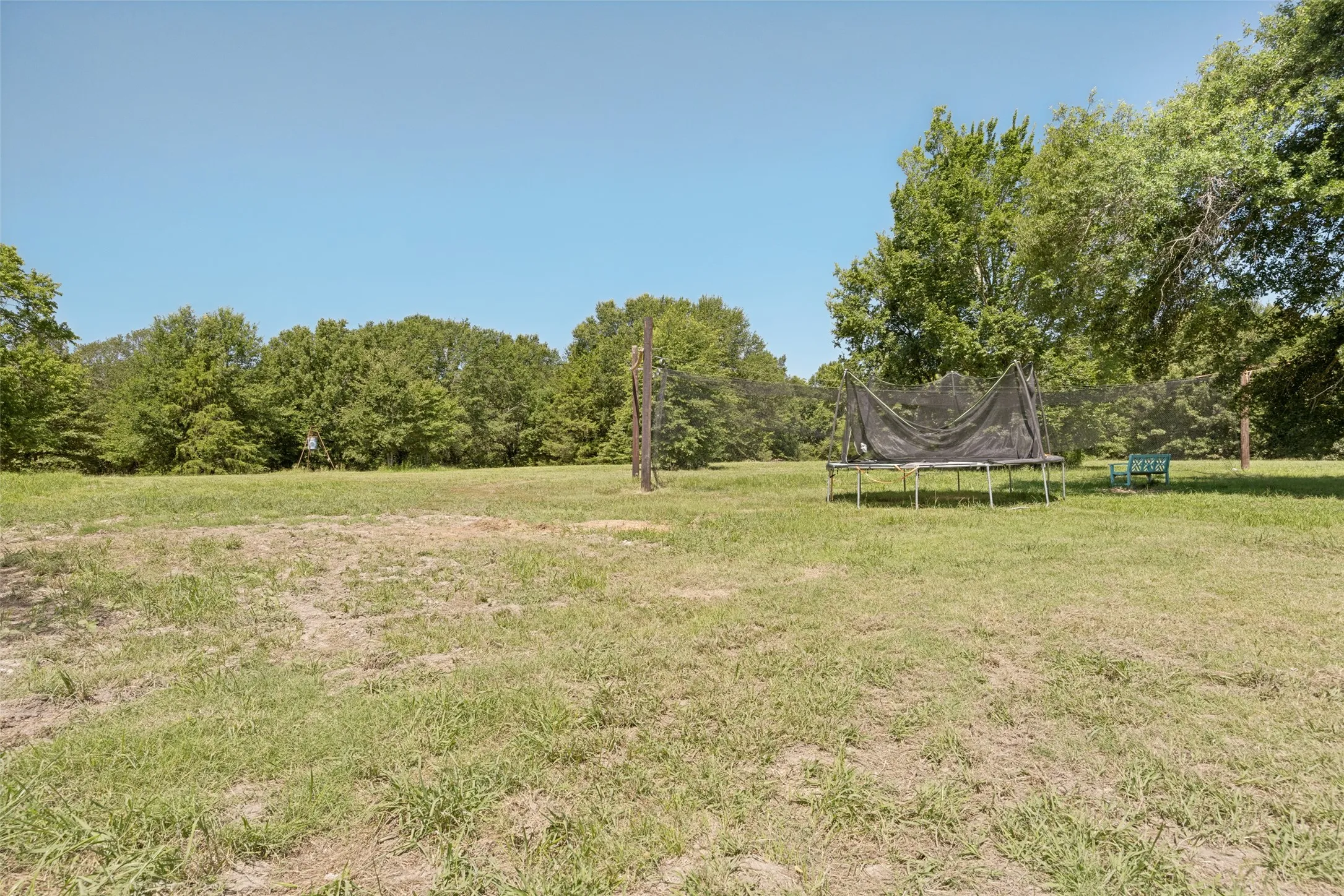 Expansive outdoor space featuring a large grassy area and mature perimeter trees
