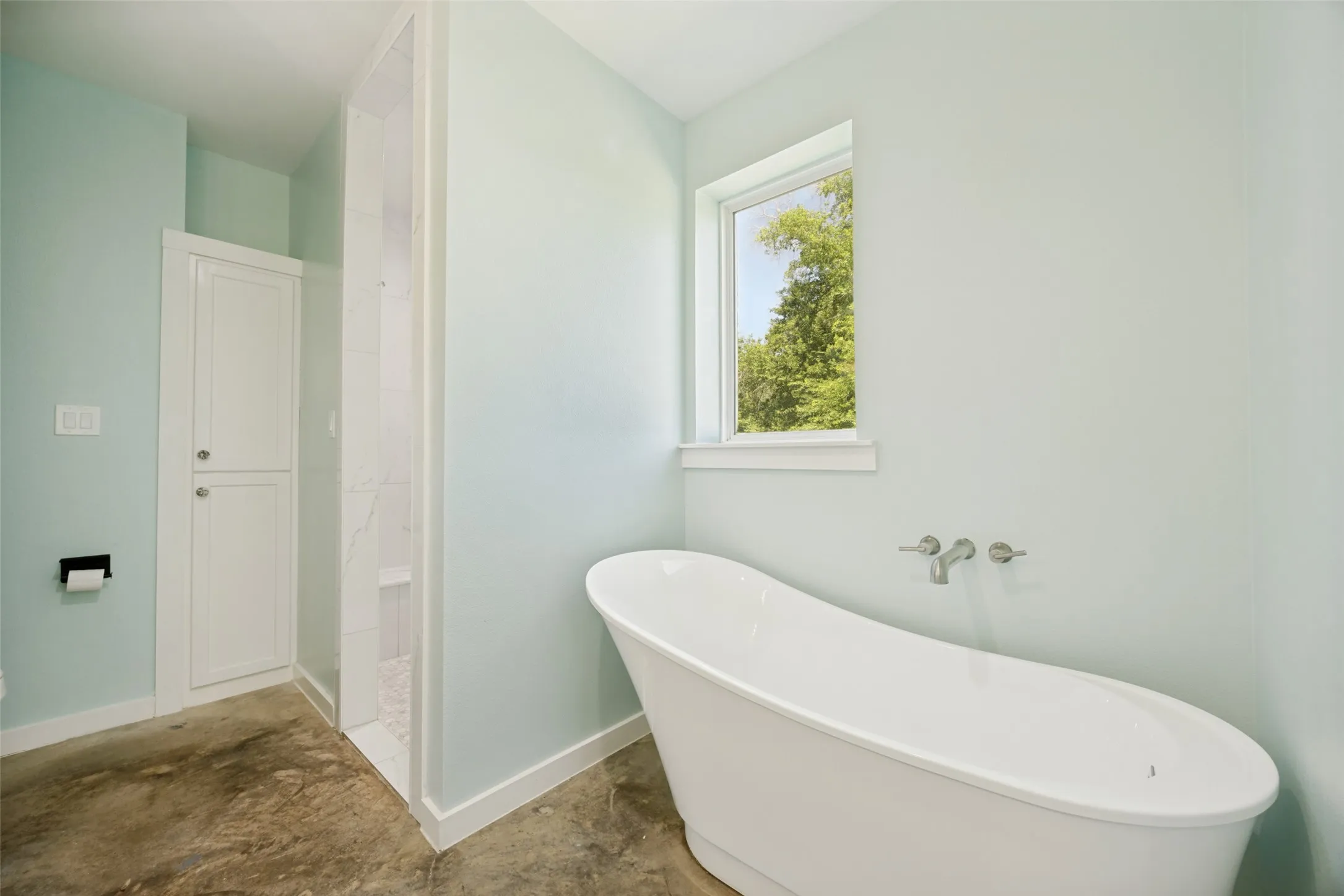 Freestanding soaking tub with wall-mounted fixtures