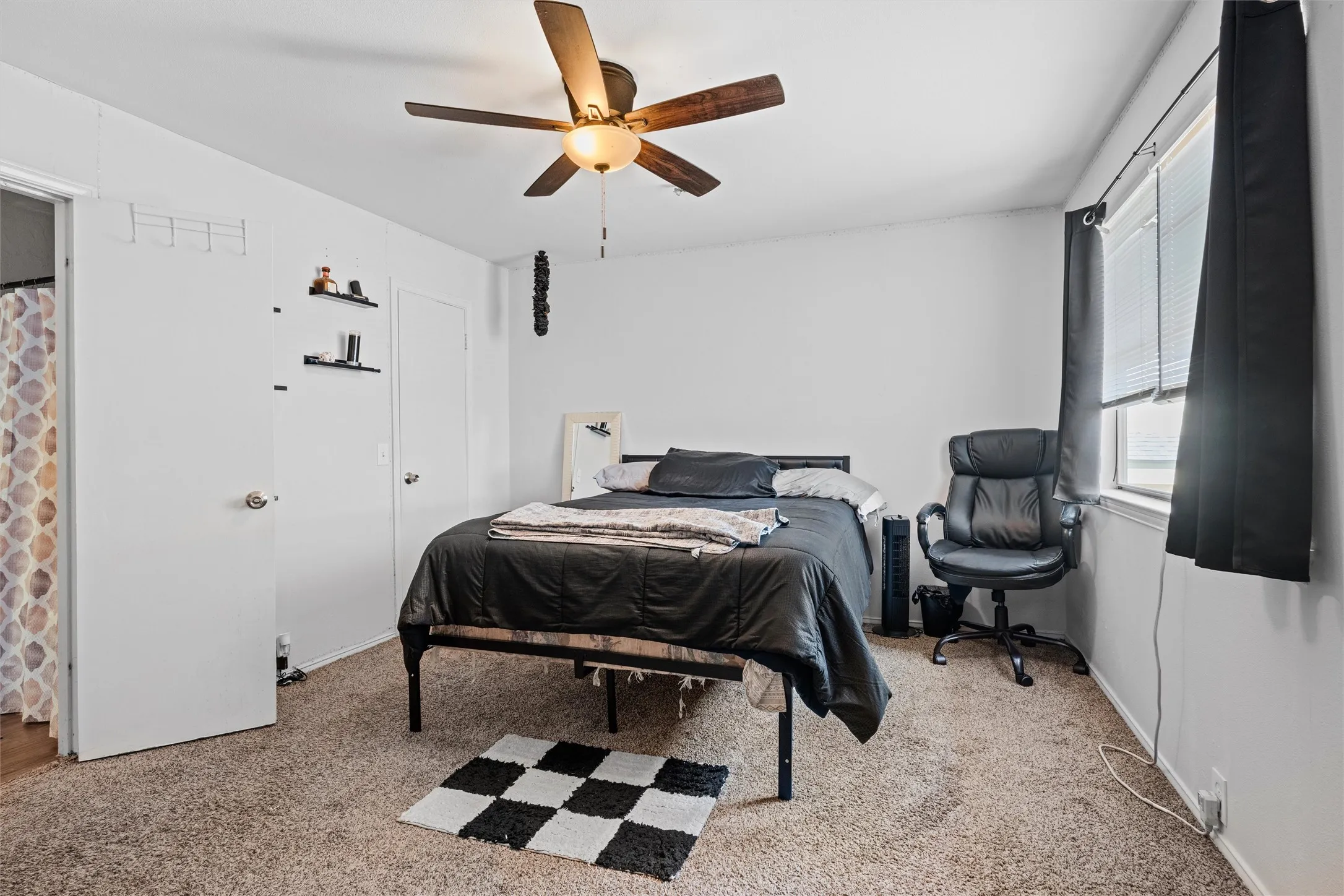 Carpeted room with a ceiling fan, window with blinds, and white walls