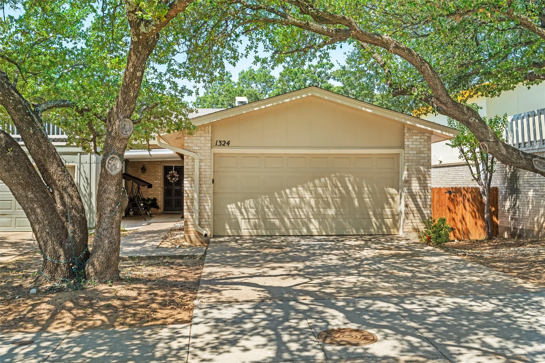 Brick and stucco exterior with an attached garage, covered entryway, and mature trees