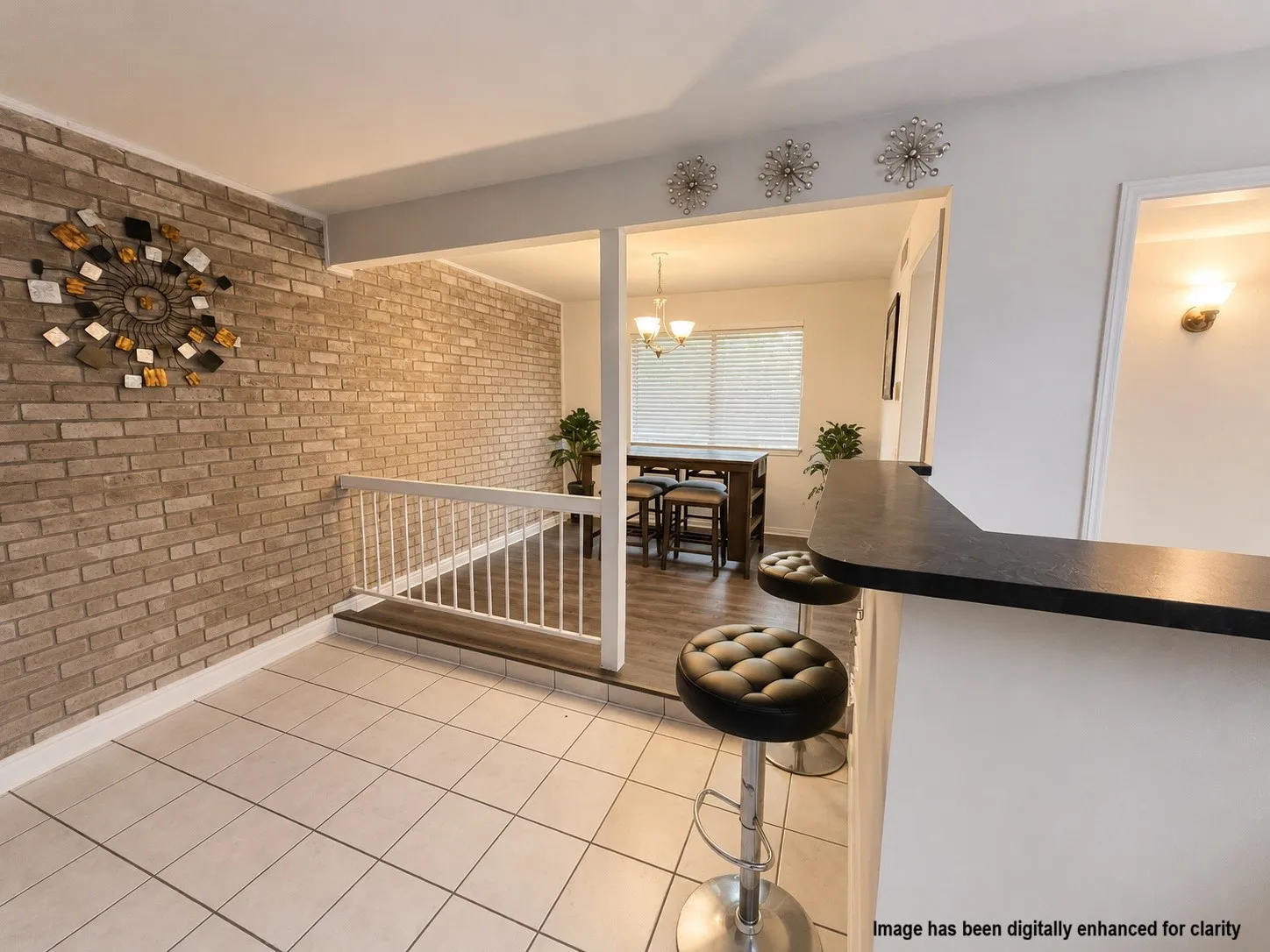 Virtually Enhanced- Exposed brick accent wall, tile flooring, ceiling fan, and open-concept design with a breakfast bar