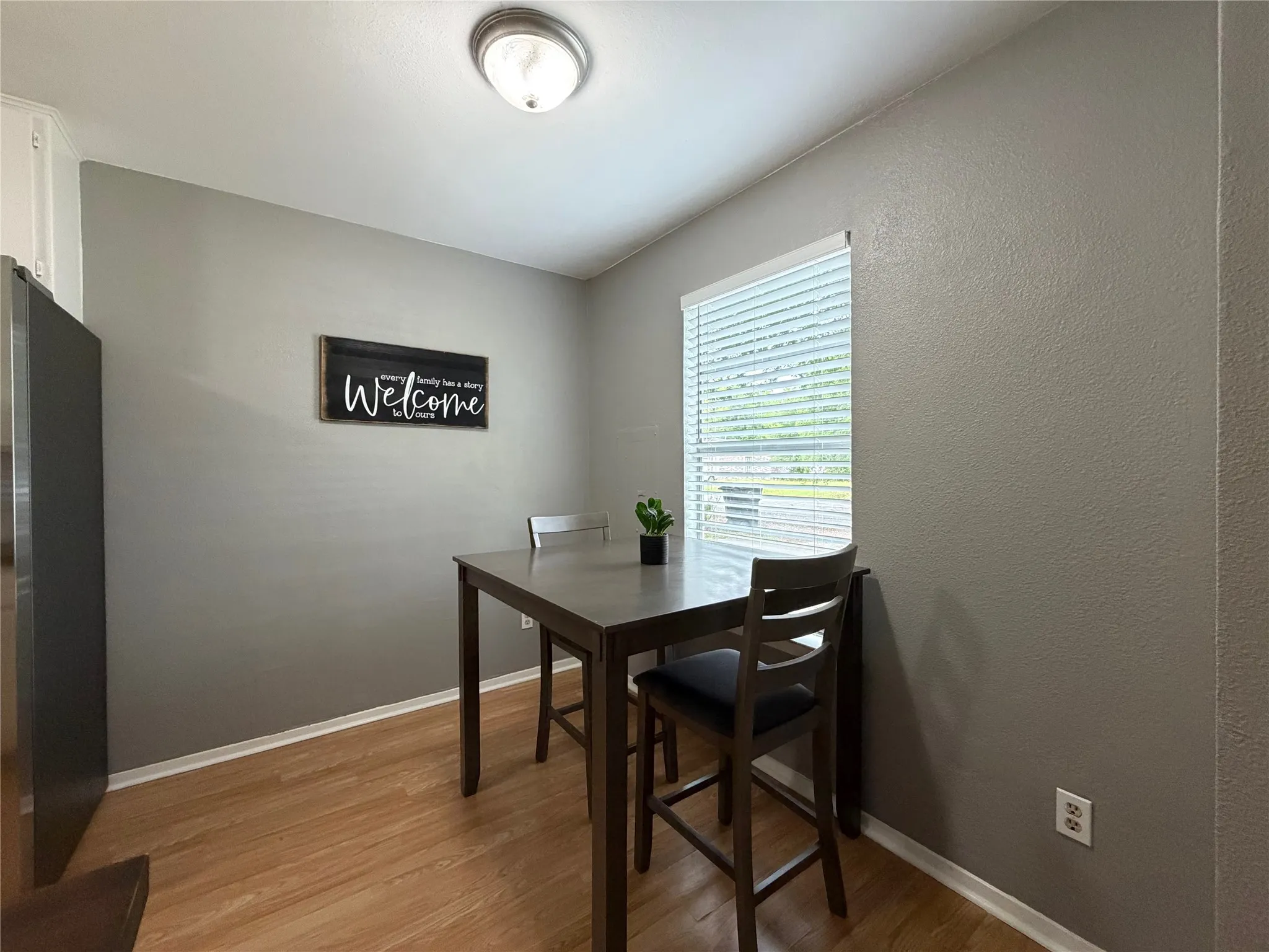 Dining area featuring wood-finish flooring, gray painted walls, and a ceiling-mounted light fixture