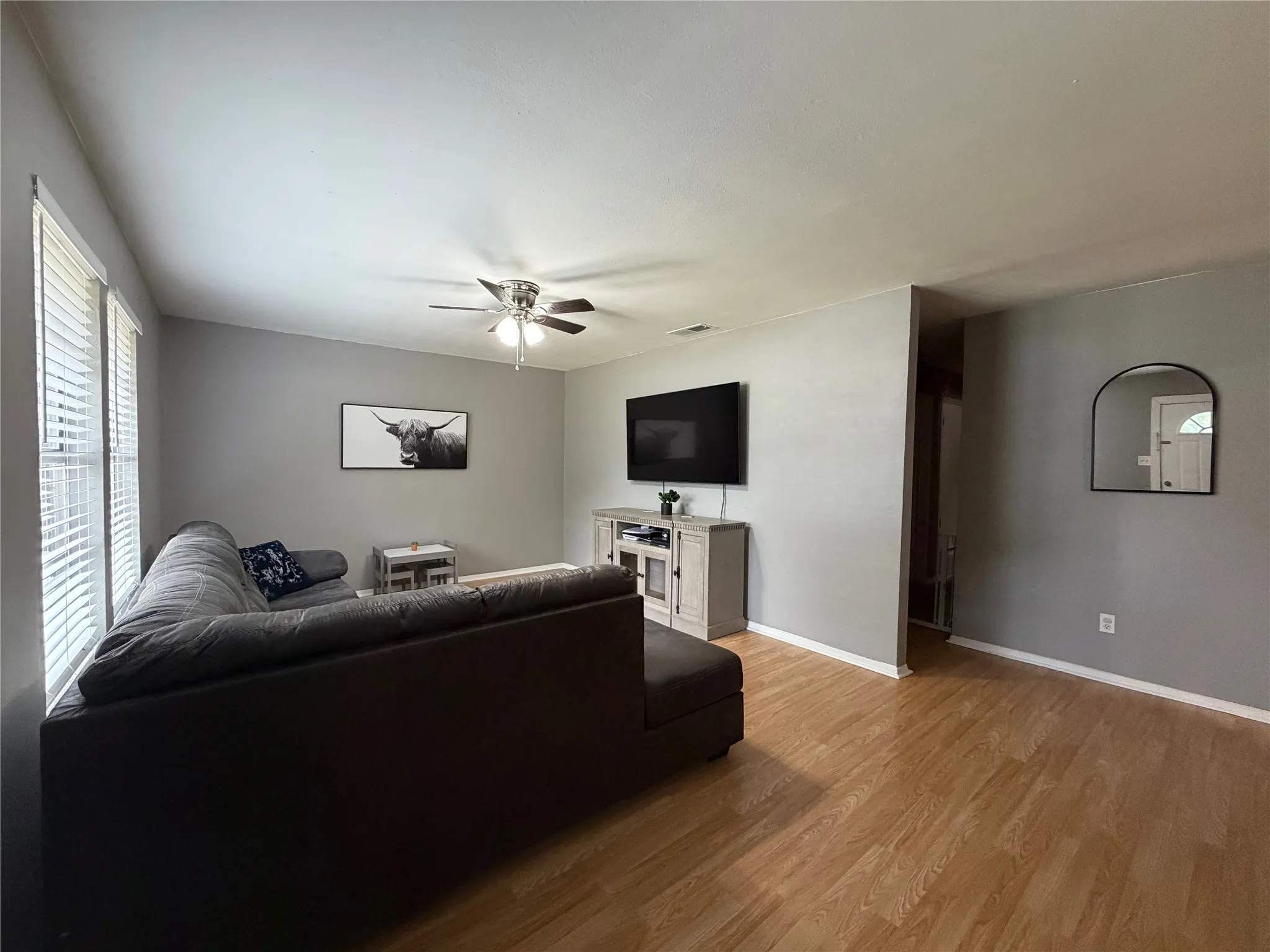 Spacious living area featuring wood-finish flooring, light gray wall tones, and white baseboards