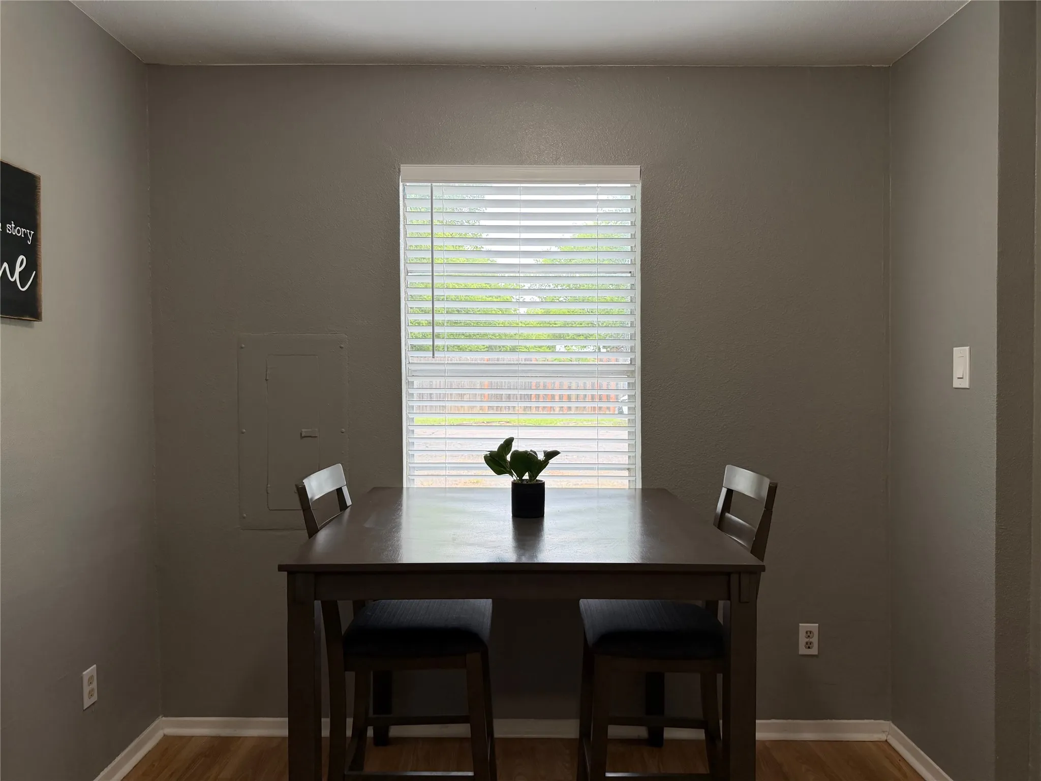 Dining area featuring neutral wall tones, a single window with white blinds, and wood-finish flooring