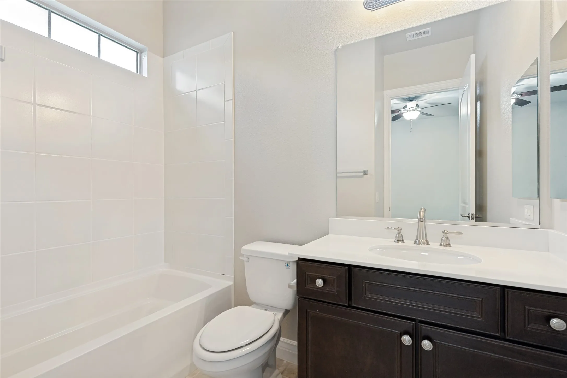 Bathroom featuring a dark wood-finish vanity with a white countertop, undermount sink, and brushed nickel fixtures