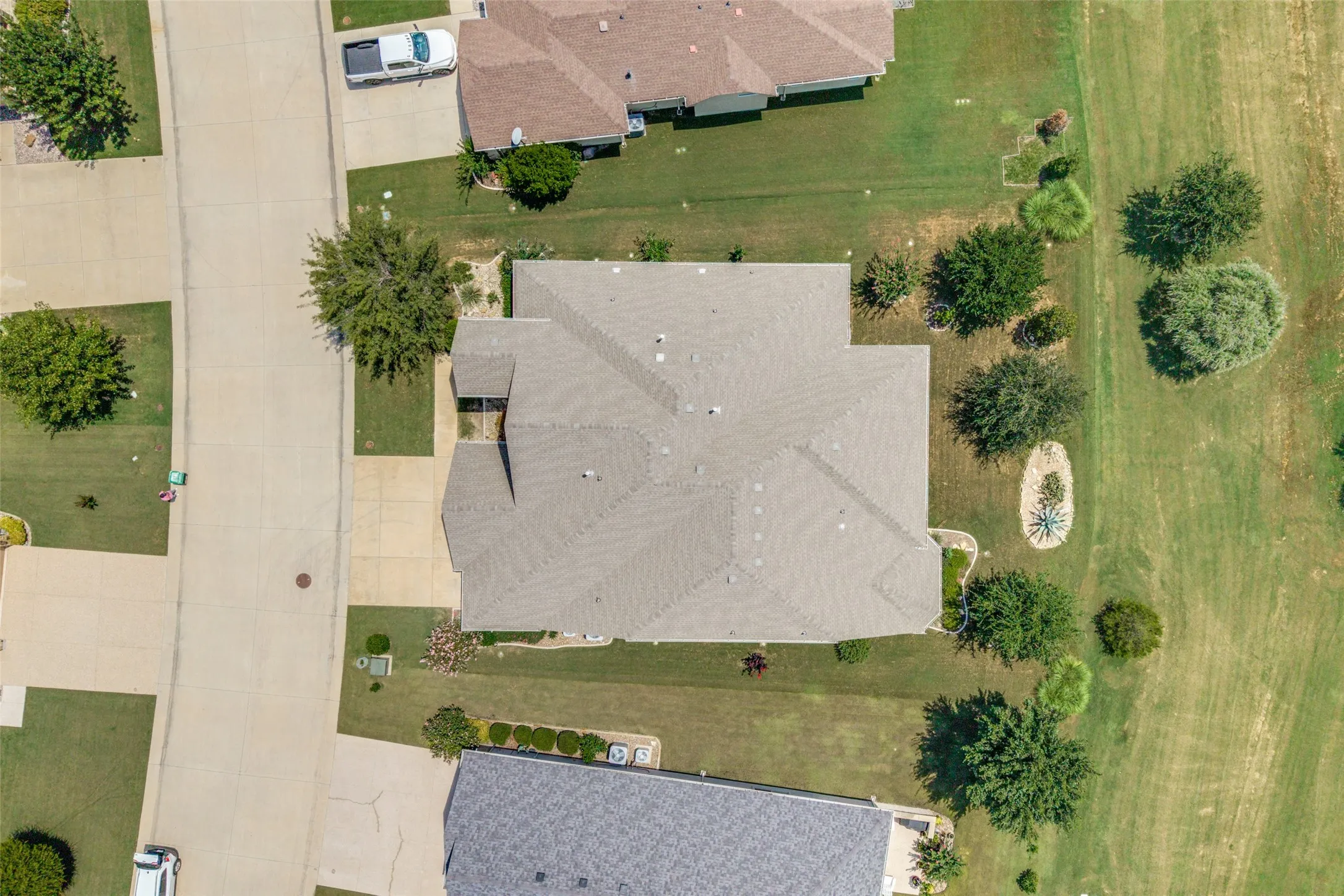 Aerial perspective showcasing the property's roofline, surrounding green space, and residential street access