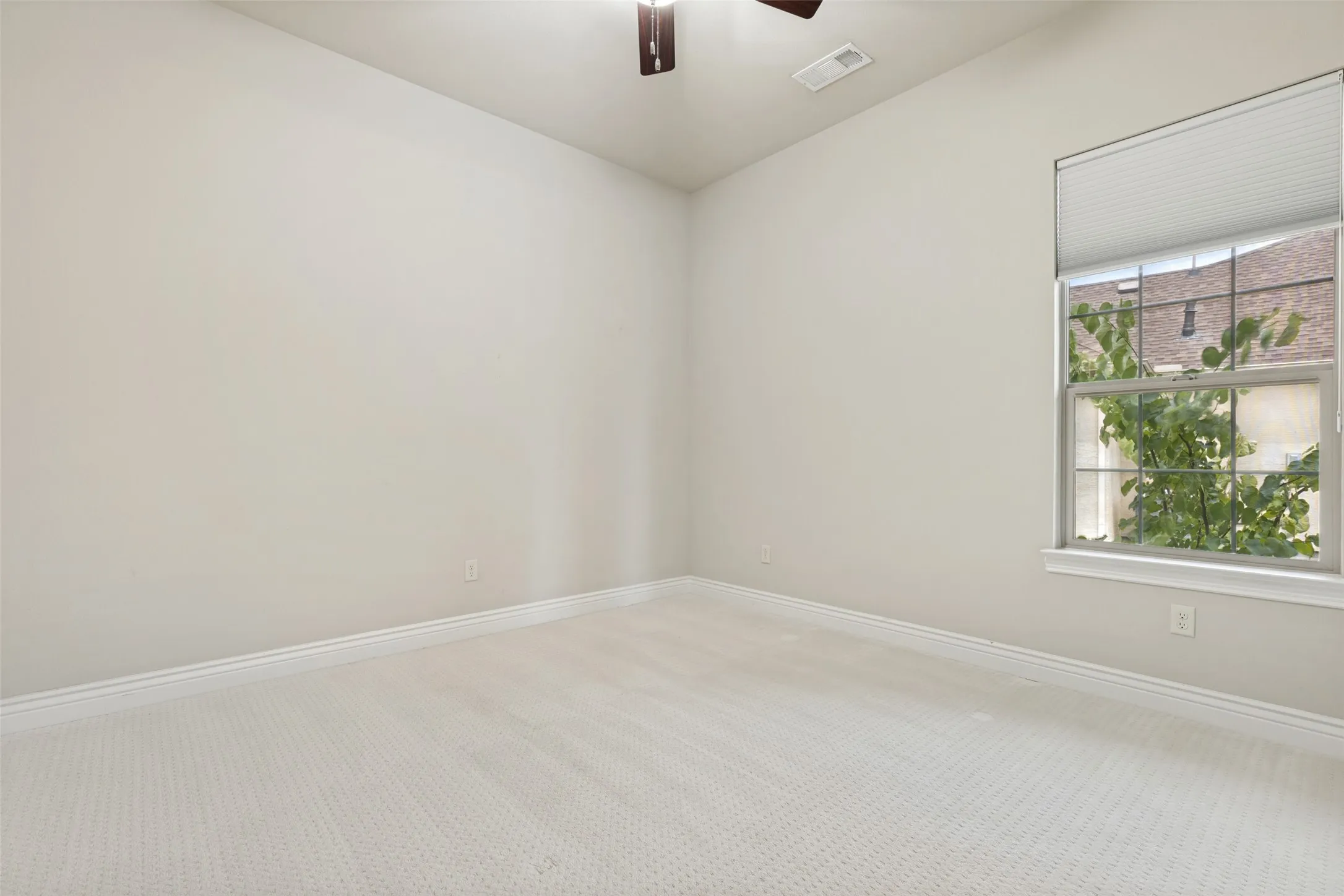 Neutral tone wall finish with a double-hung window featuring a cellular shade