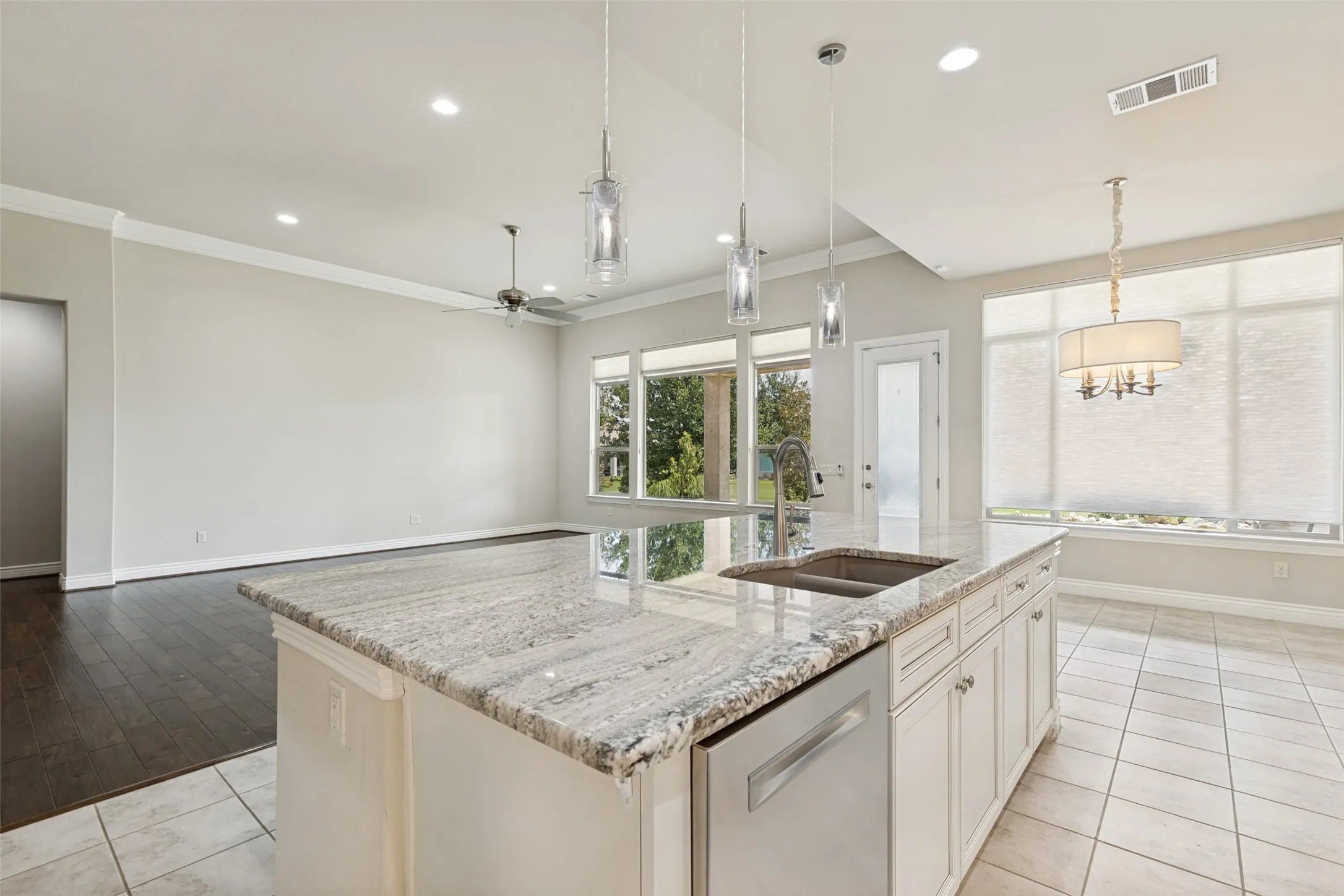 Kitchen island featuring a double basin sink, stainless steel dishwasher, and a light-toned countertop