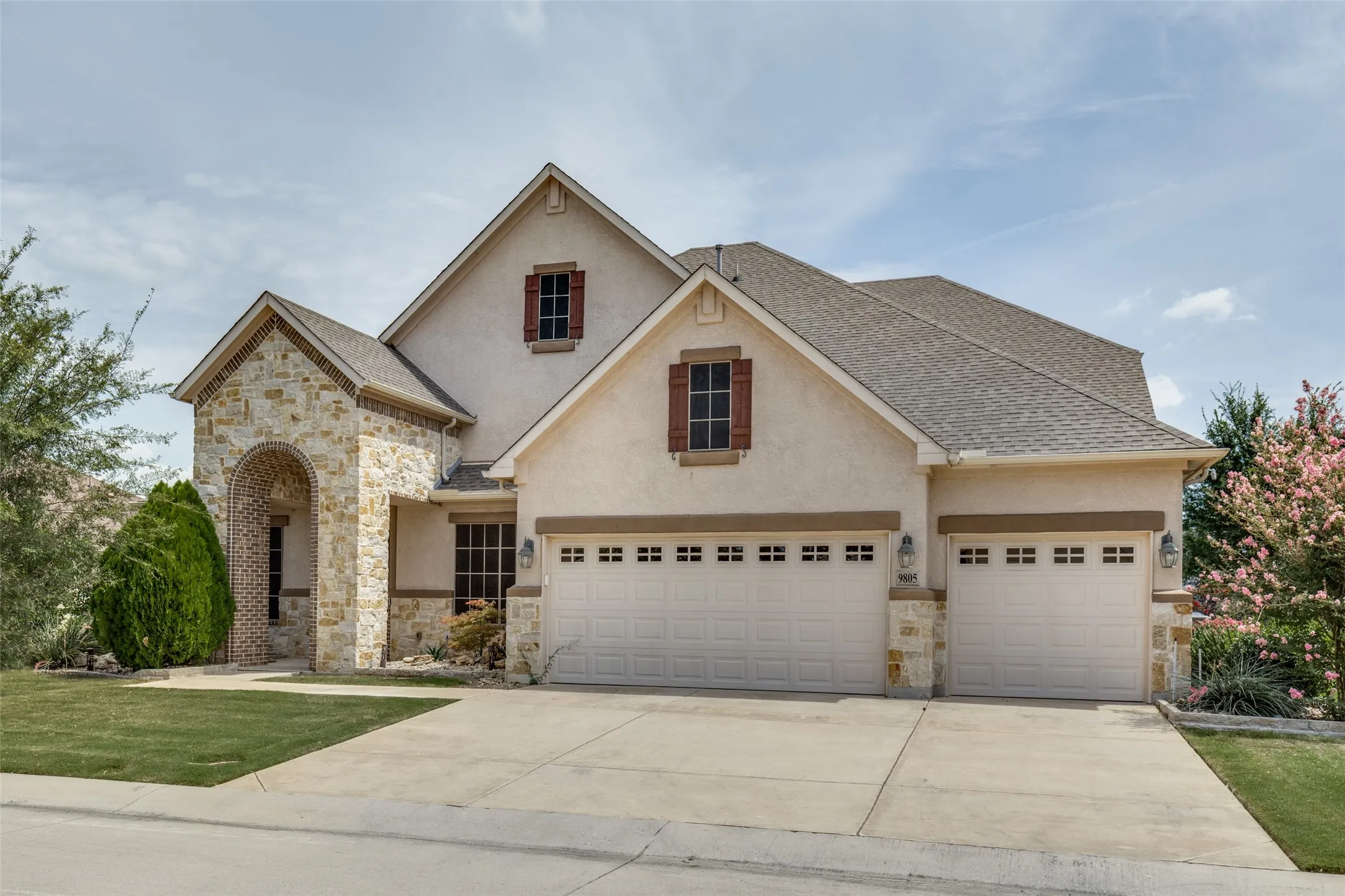 Stucco and stone facade featuring a prominent arched entry