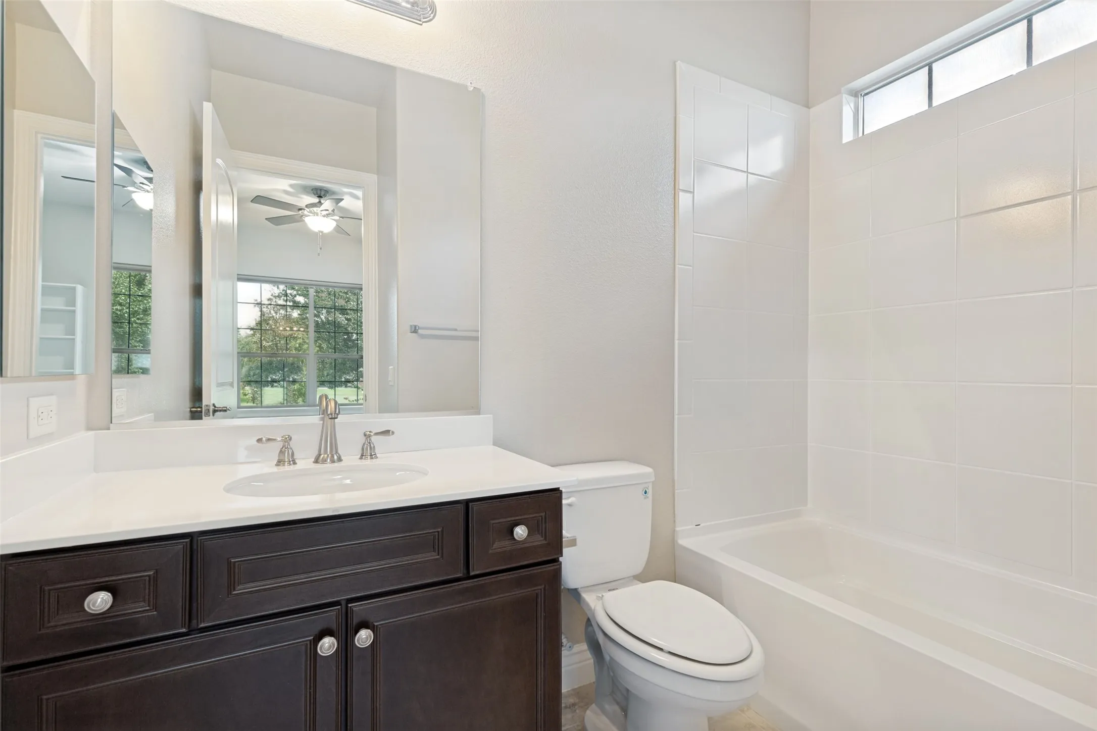 Bathroom featuring a dark wood-finish vanity with a white countertop and undermount sink, brushed nickel faucet, and a large mirror