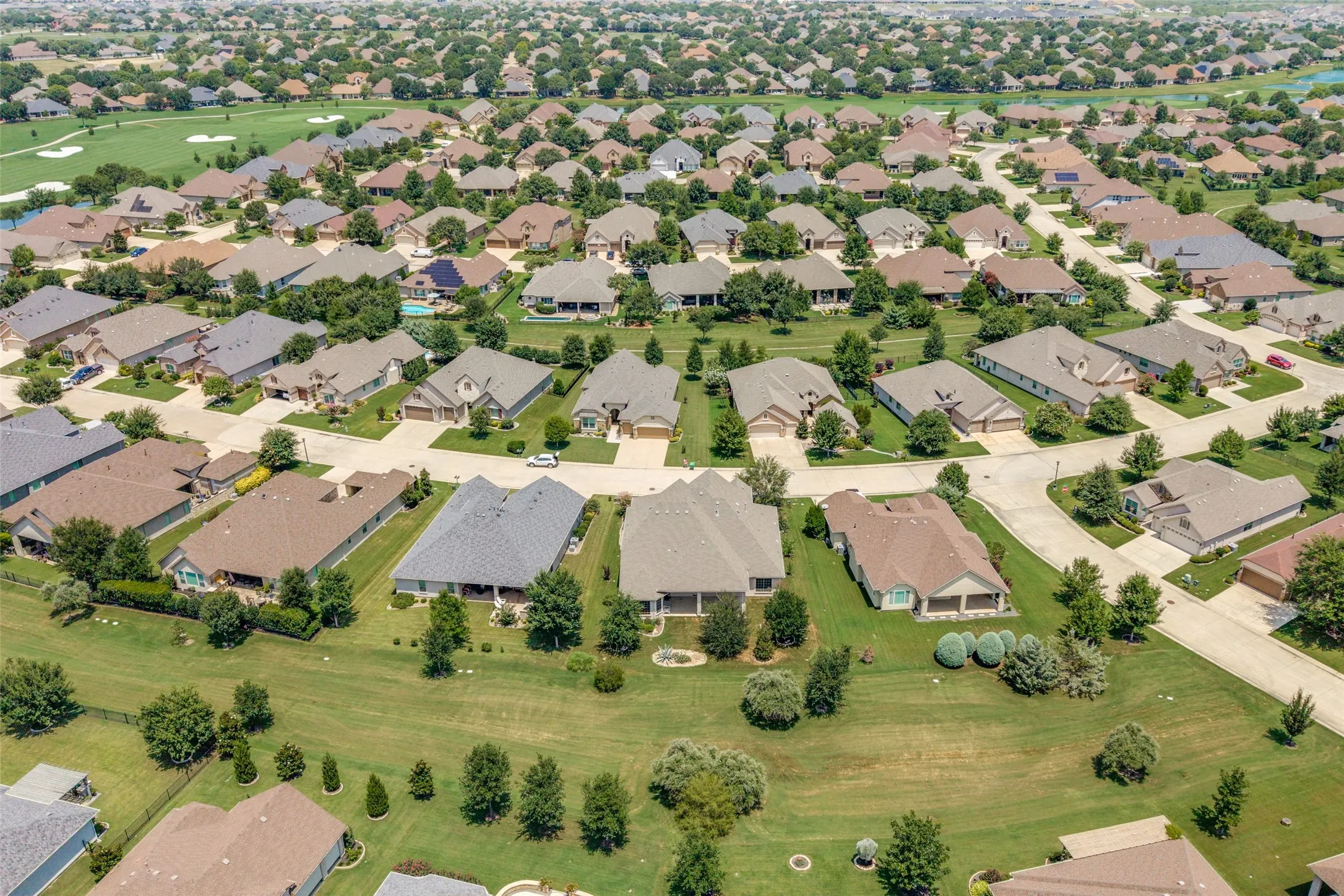 Aerial view showcasing a residential community with numerous single-story homes, individual driveways, and green lawns