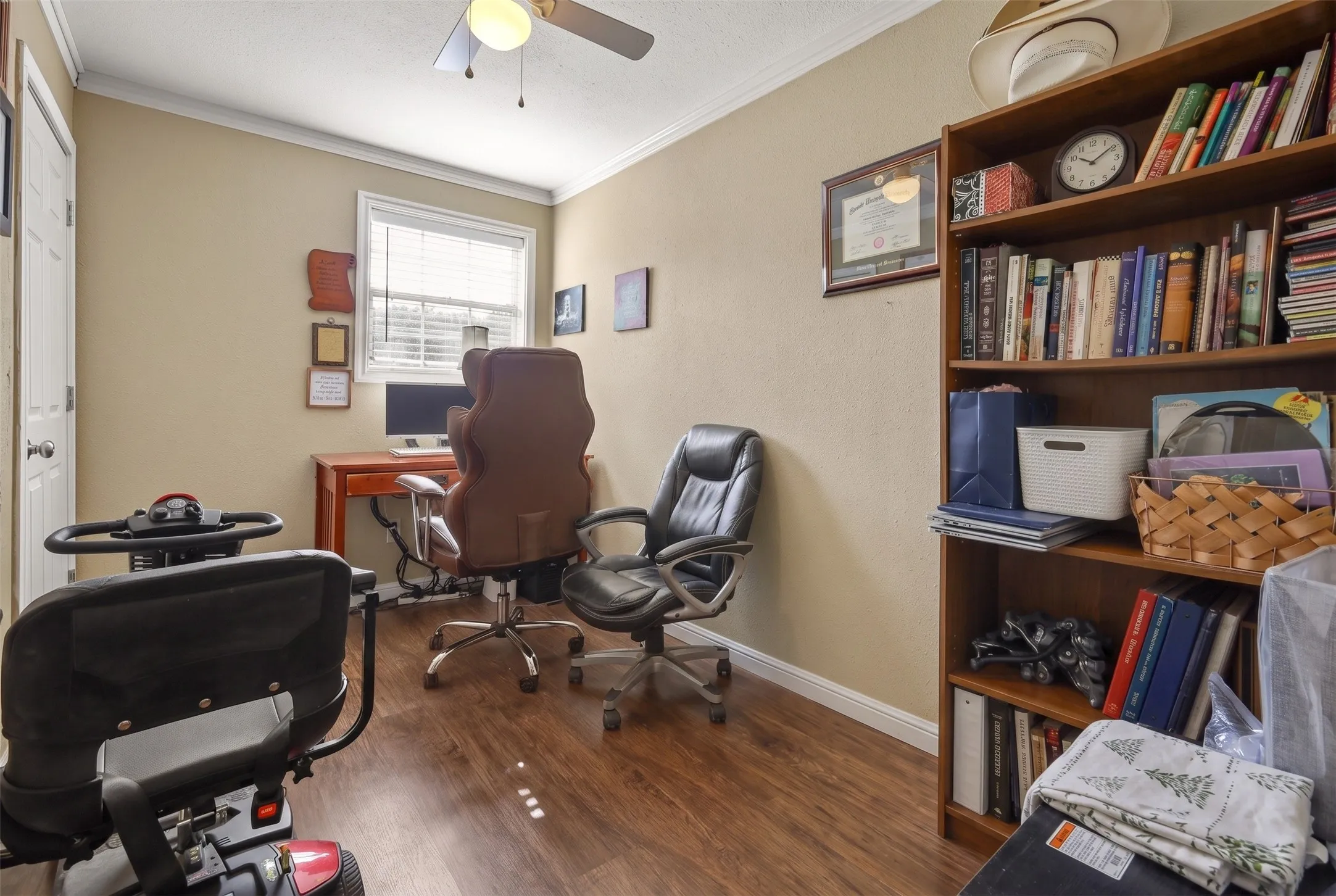 Room featuring wood-finish flooring, a ceiling fan with light fixture, and a window with blinds
