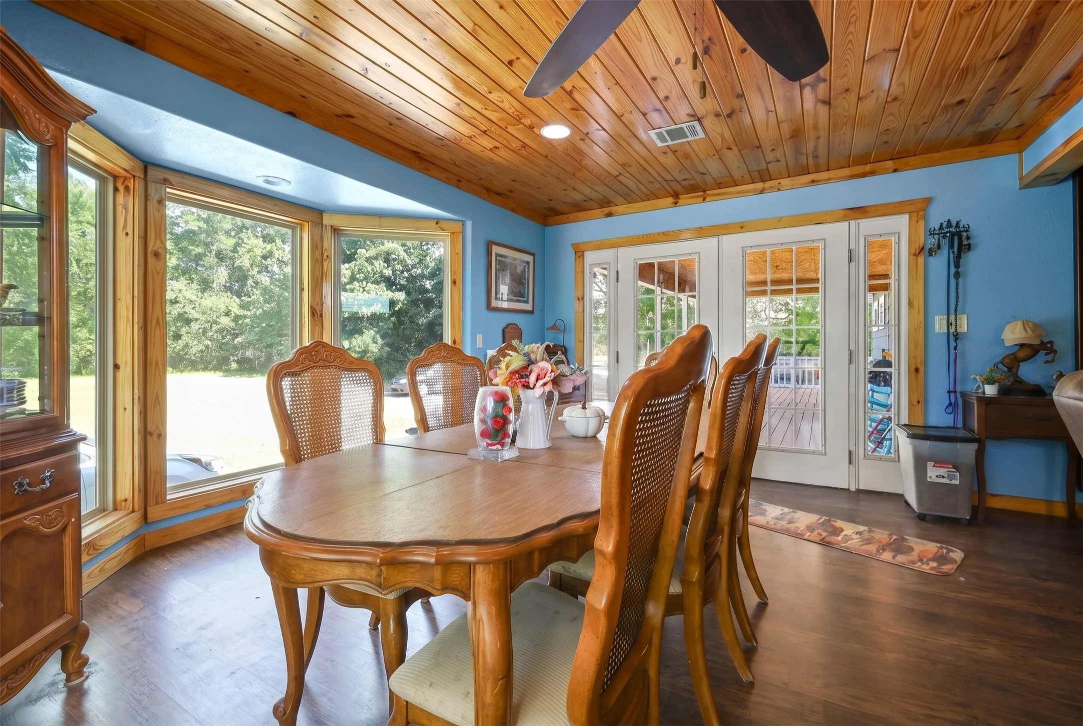 Dining space featuring a natural wood plank ceiling, a bay window with wood trim, and wood-finish flooring