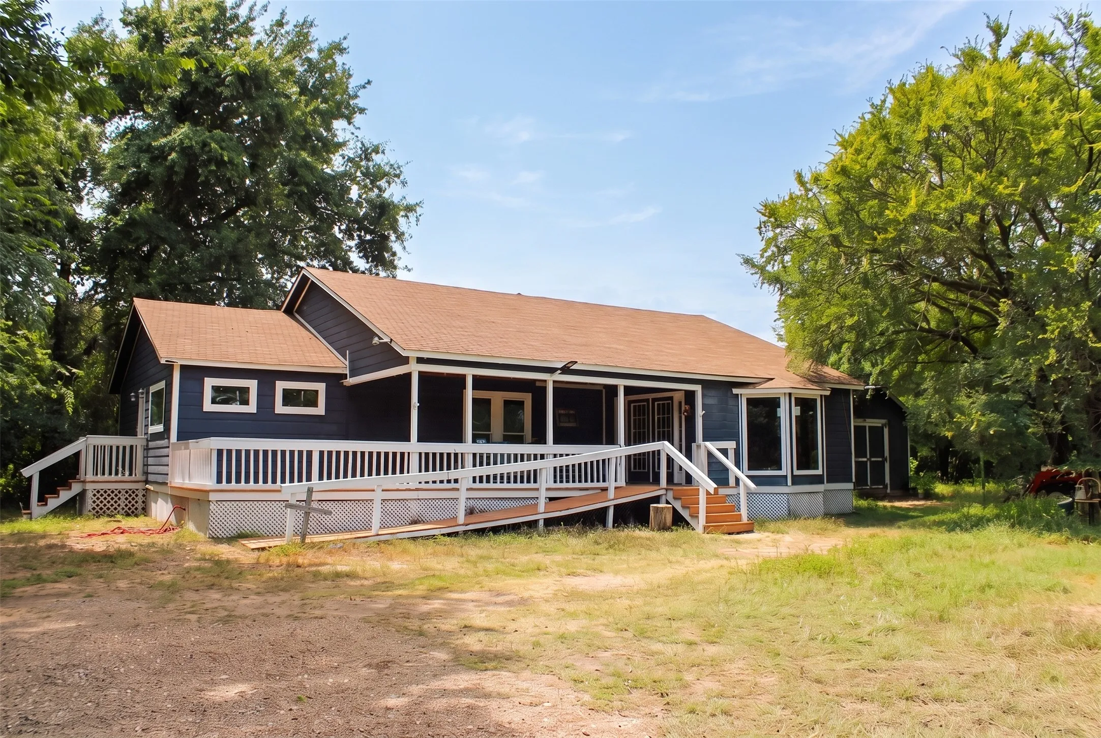 Blue-sided single-story residence featuring a brown shingle roof, white trim, and a full-length covered porch