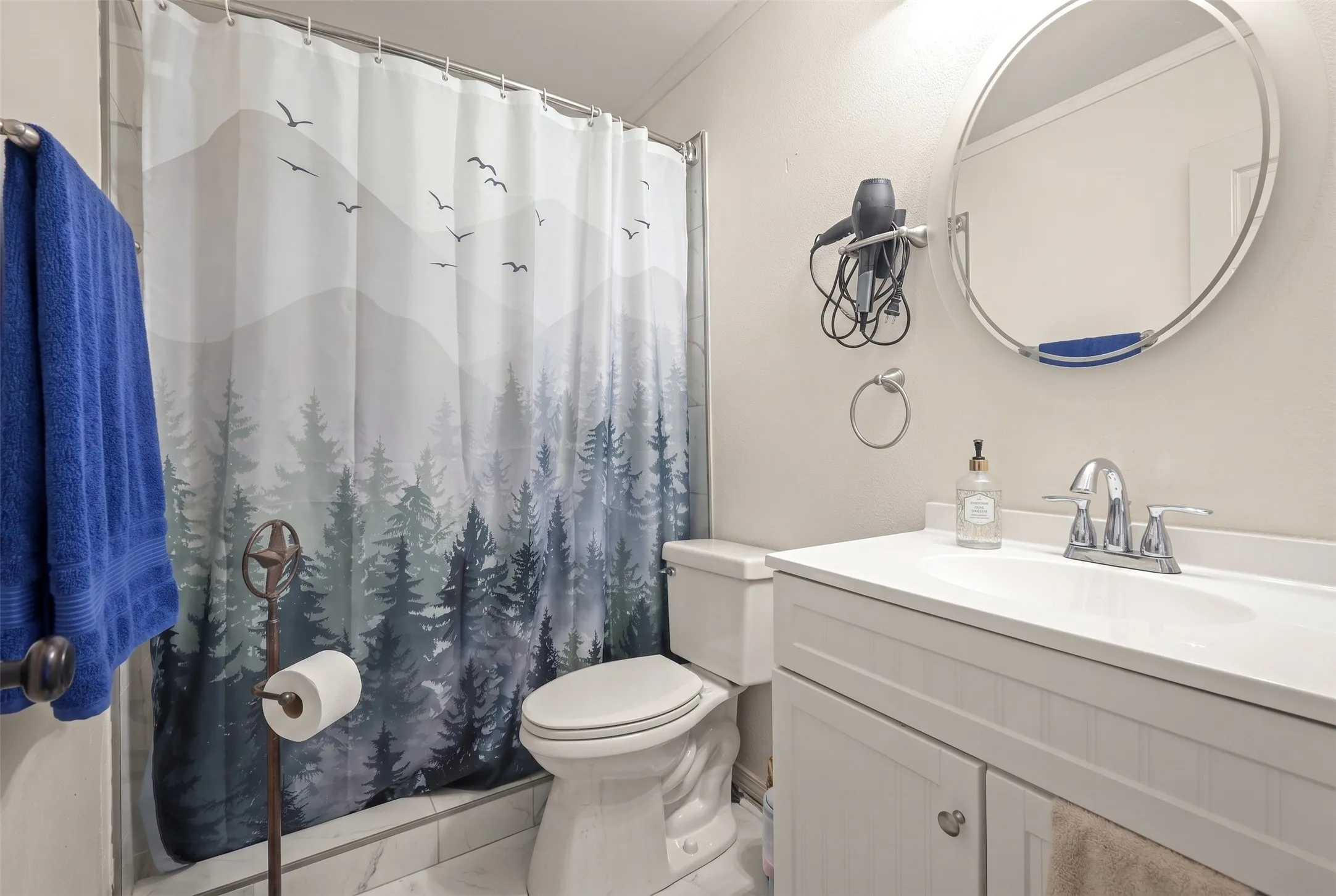 Bathroom featuring a white vanity with integrated sink, chrome faucet, and a round mirror
