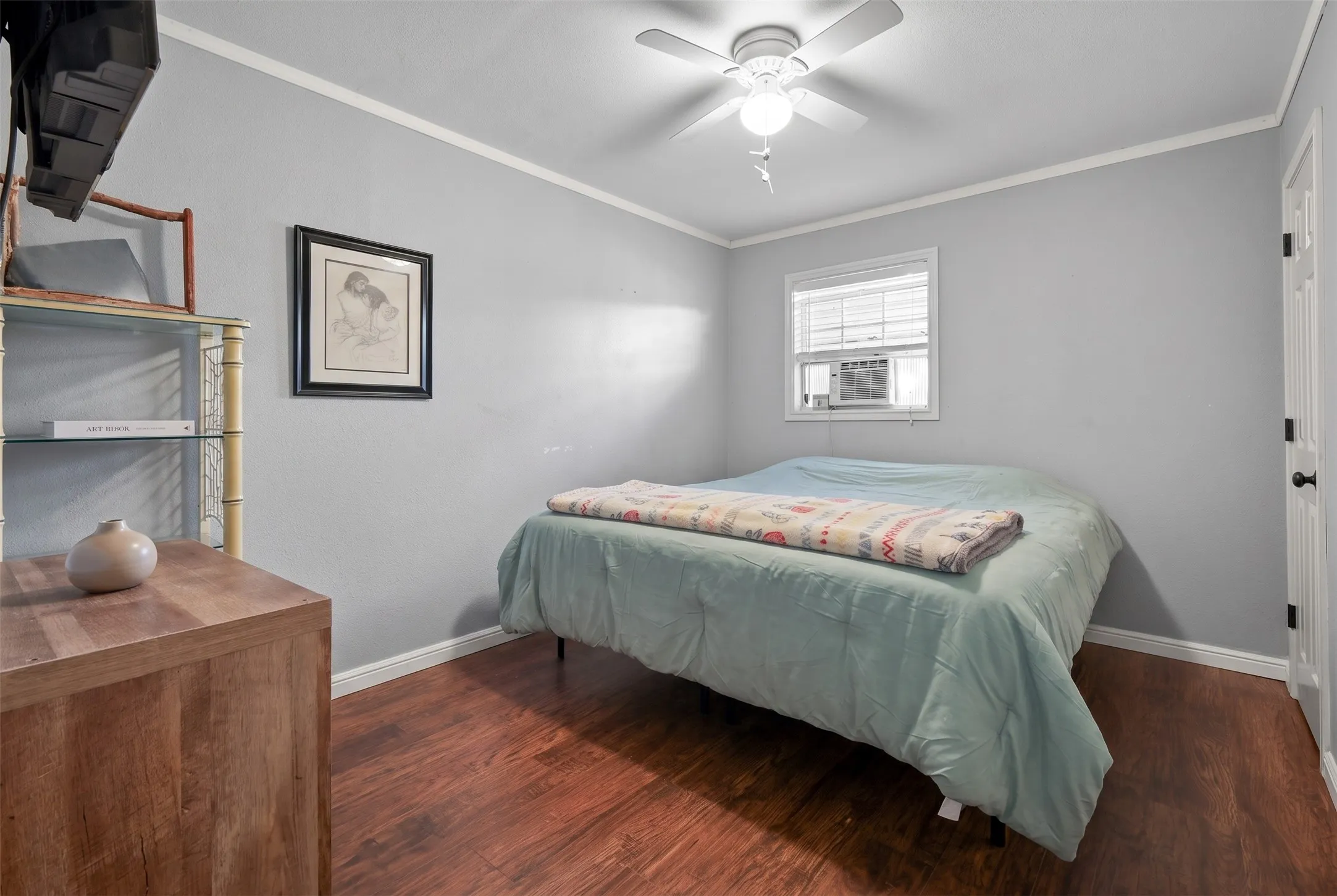 Interior room featuring wood-finish flooring, light gray walls, and white crown molding