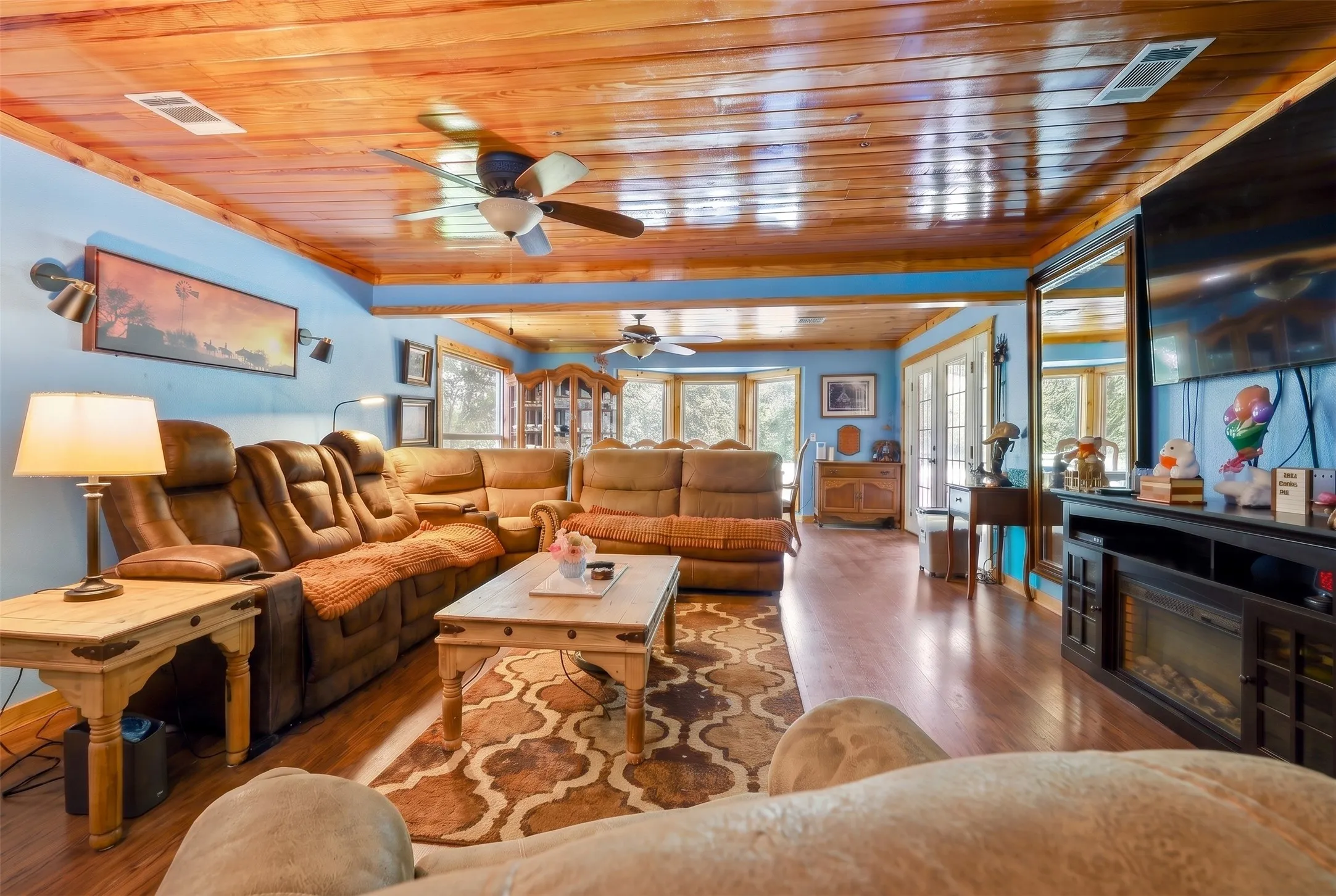 Spacious living area featuring wood-finish flooring, a wood-paneled ceiling, and light blue walls