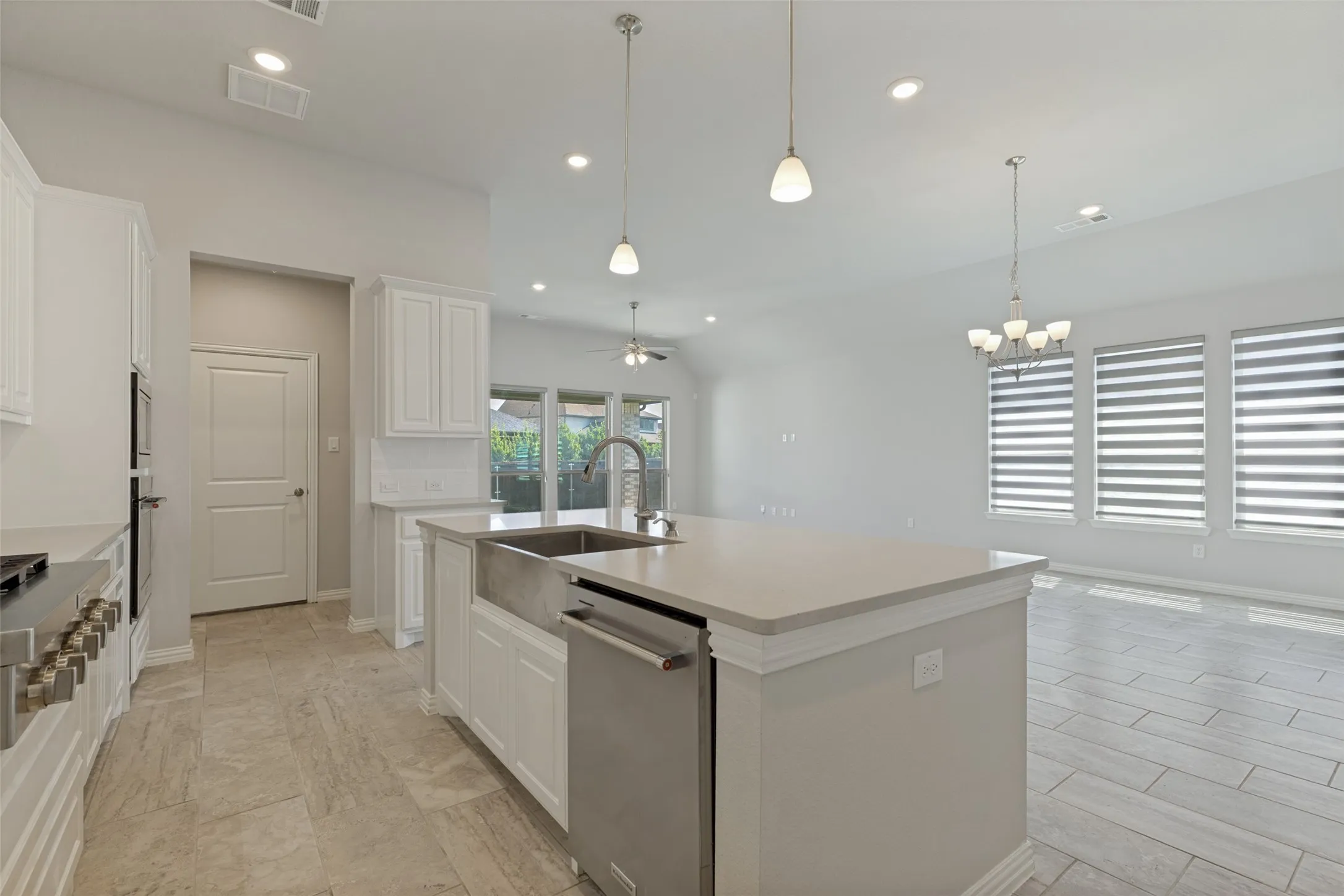 Open-concept kitchen featuring an oversized island with a farmhouse sink and stainless steel dishwasher