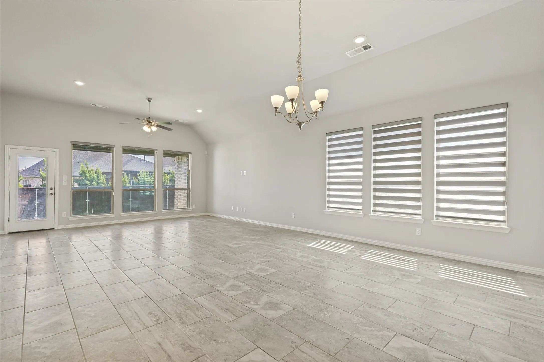 Spacious living area featuring large format tile flooring, vaulted ceilings, and recessed lighting