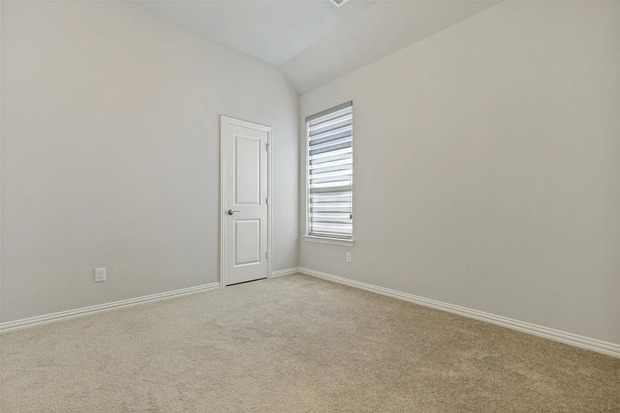 Bright secondary bedroom with vaulted ceilings,adjacent to a full bathroom