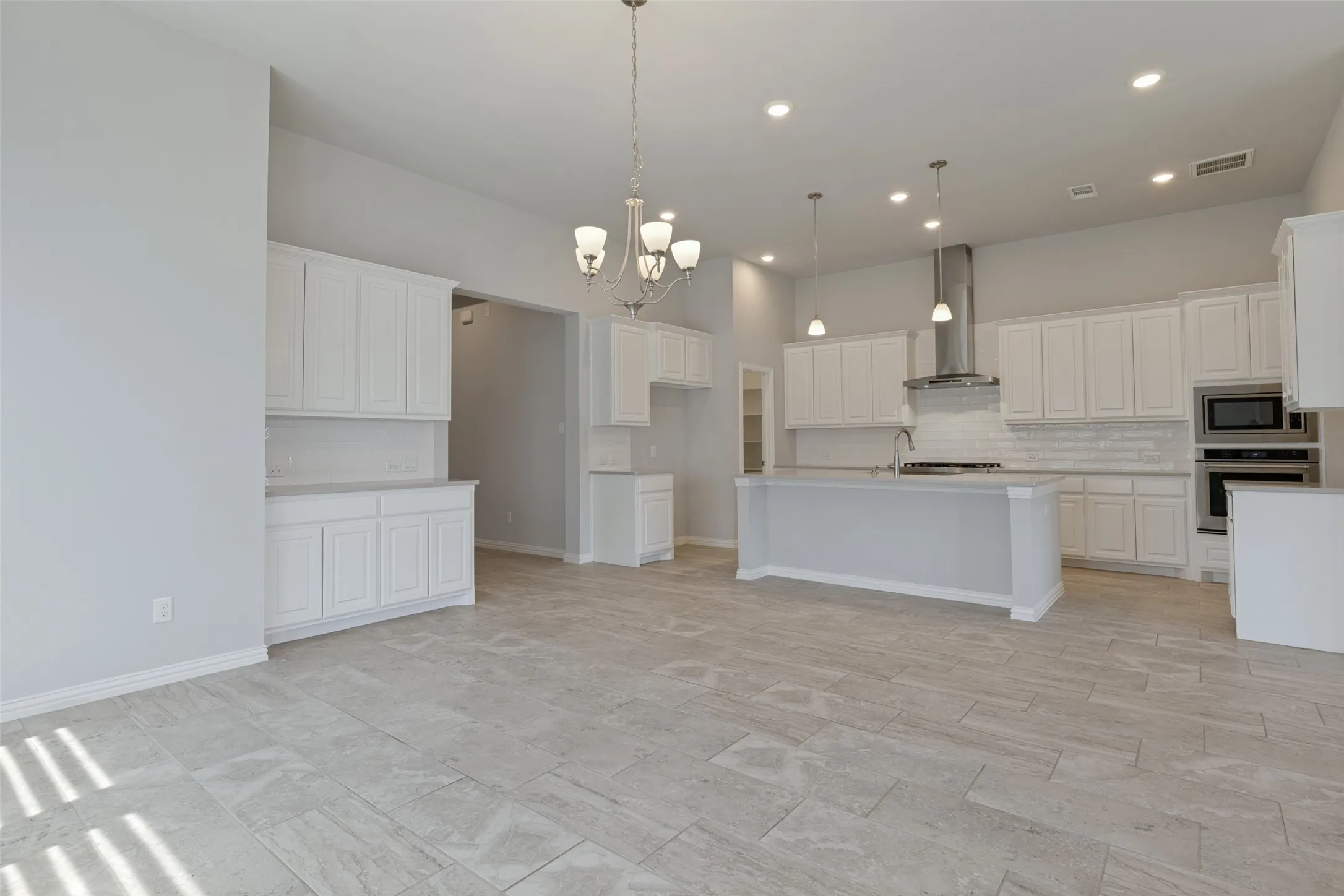 Open-concept kitchen featuring an oversized island, white shaker cabinetry, stainless steel appliances, a subway tile backsplash, and recessed lighting