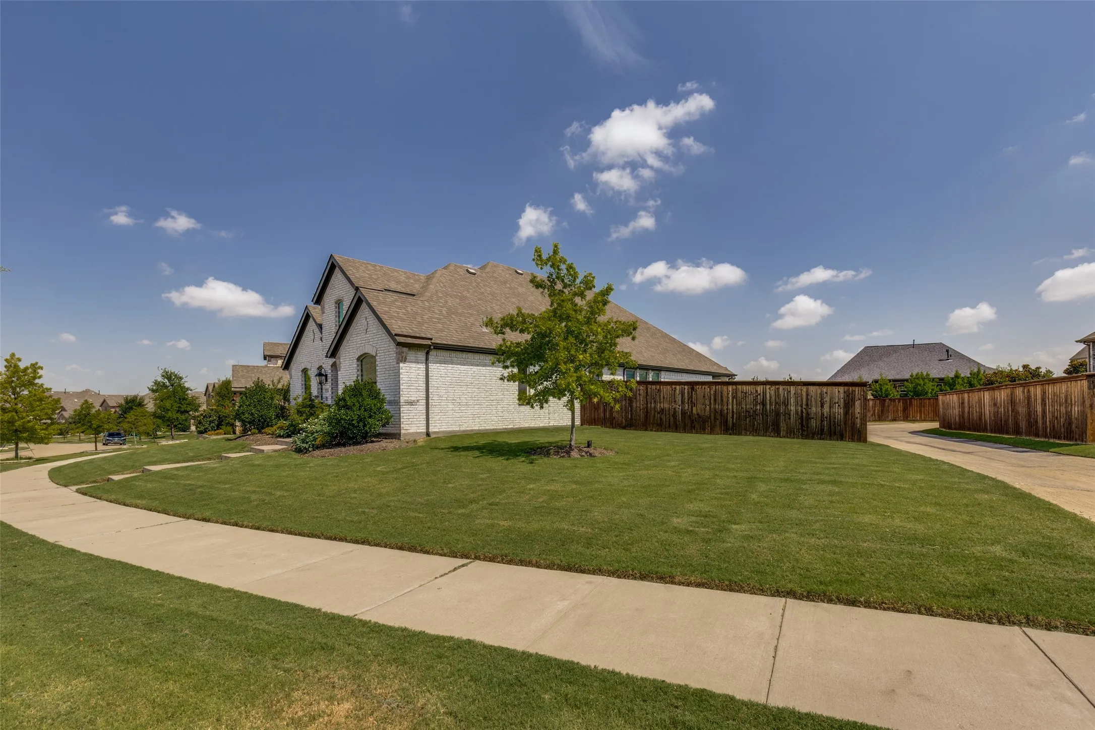 White brick exterior with dark trim and a brown shingle roof