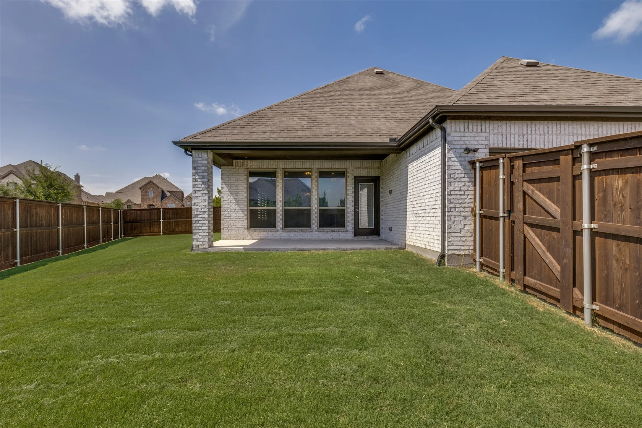 Expansive backyard featuring a manicured lawn, a full privacy fence, and a concrete patio