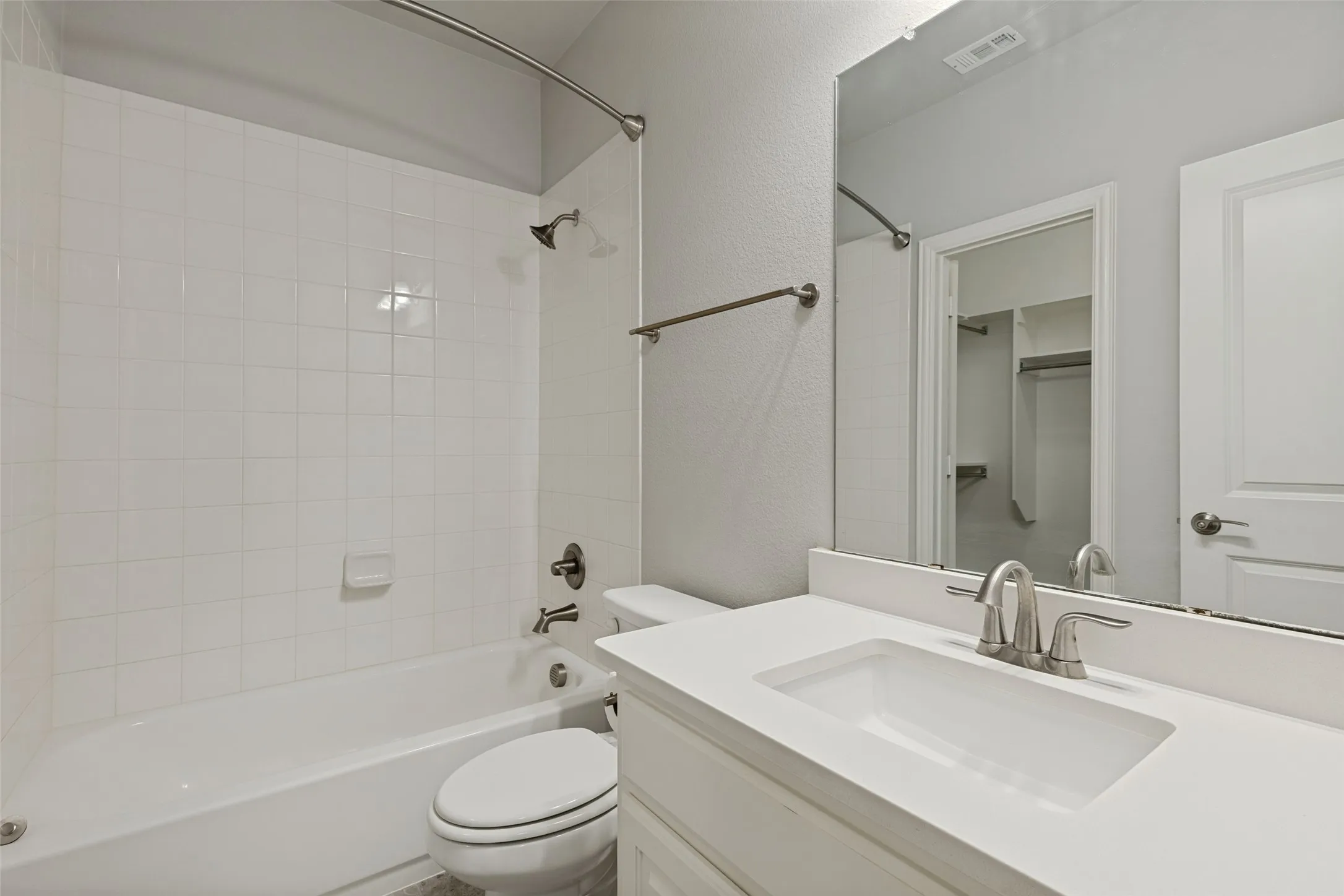 Full bathroom featuring a white tub with tile surround, a toilet, and a vanity with an integrated sink