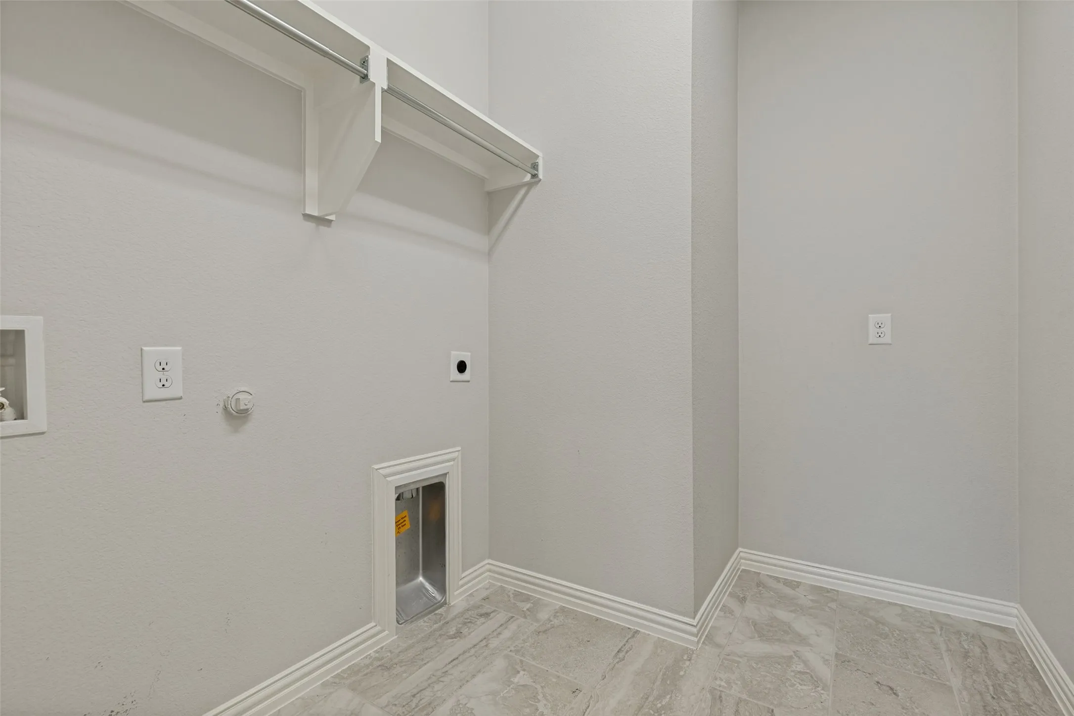 Utility space featuring light gray walls, layered baseboards, and gray marble-look floor tiles