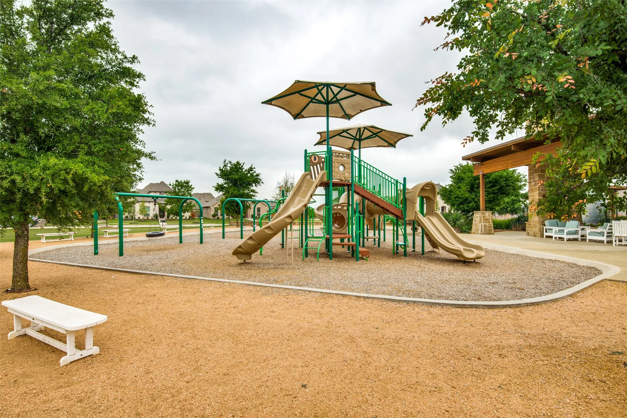 Community playground featuring shade umbrellas, multiple slides, and swing sets
