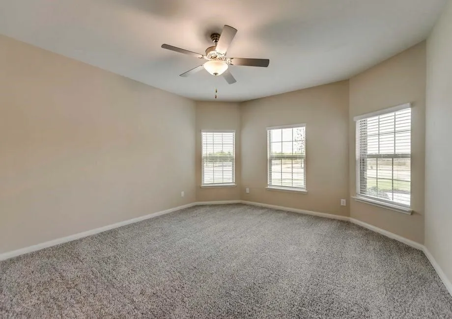 Spacious room featuring textured gray carpeting and light tan wall paint