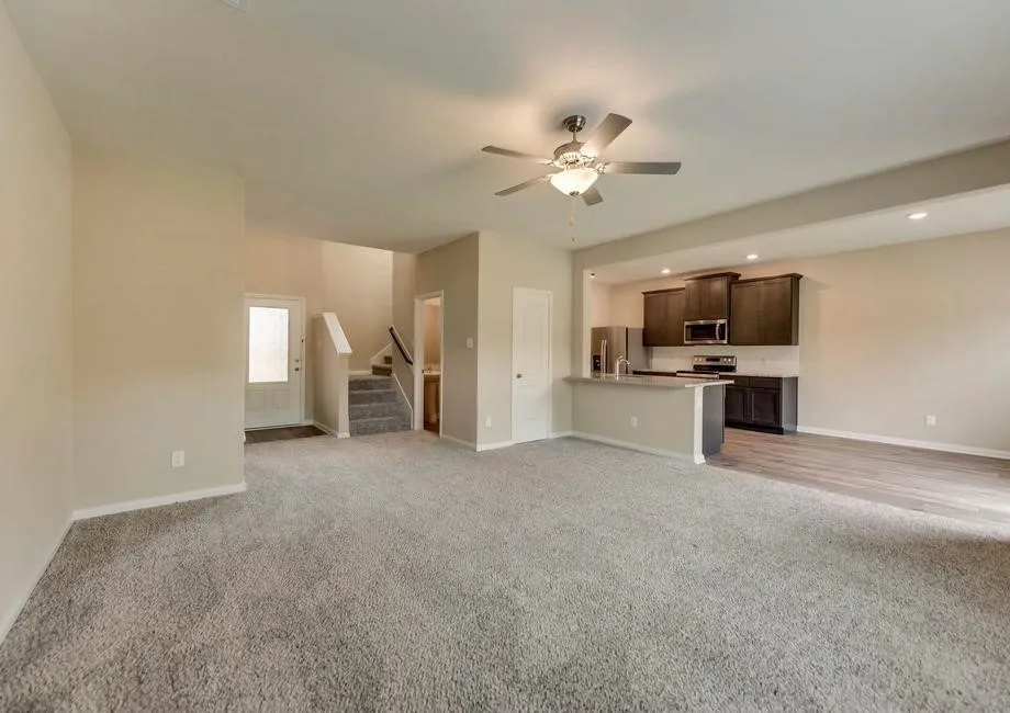 Spacious main living area featuring neutral carpeting, a ceiling fan with integrated lighting, and recessed ceiling lights
