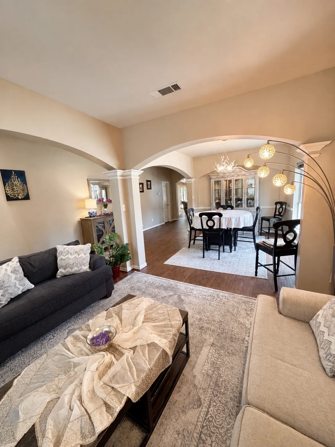 Open-concept living spaces featuring arched architectural details, wood-finish flooring throughout, and abundant natural lighting