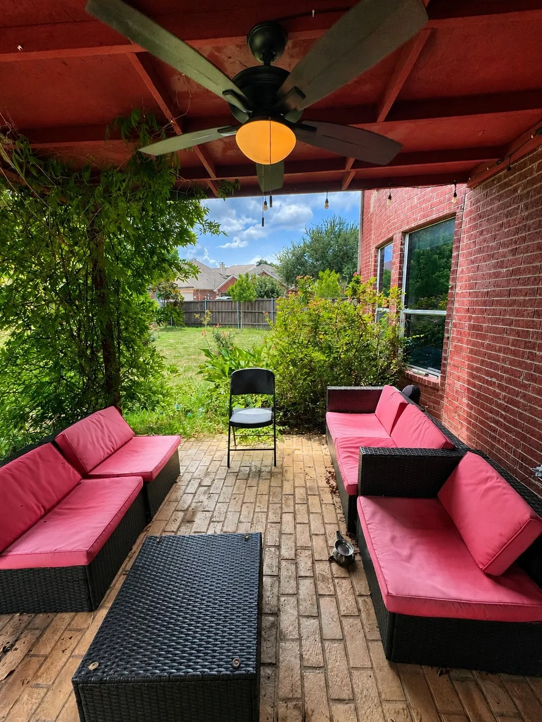 Covered patio with a ceiling fan, exposed wood beams, and a brick exterior wall