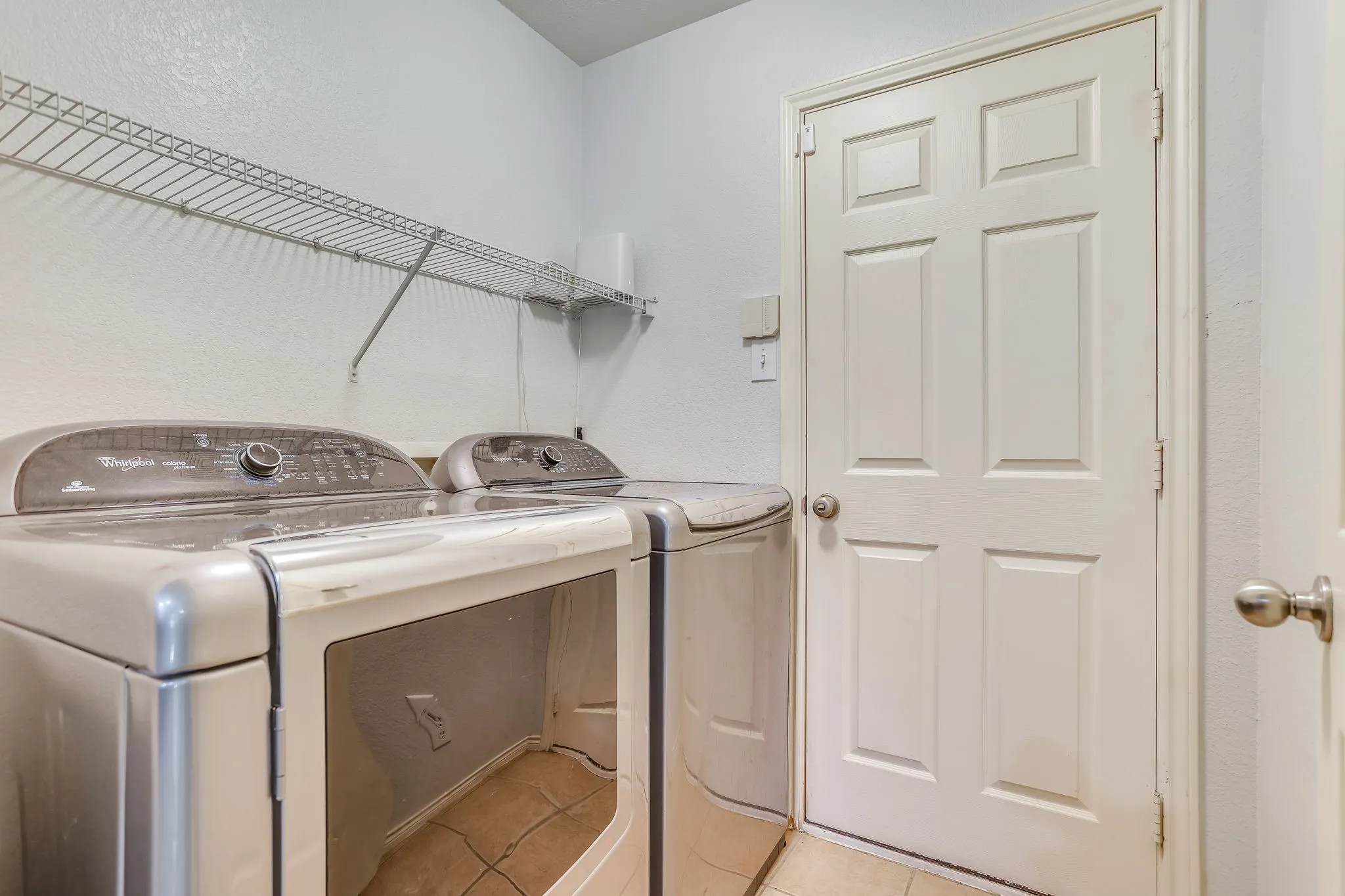 Separate utility room leads to garage. Whirlpool Washer and Dryer Convey with property
