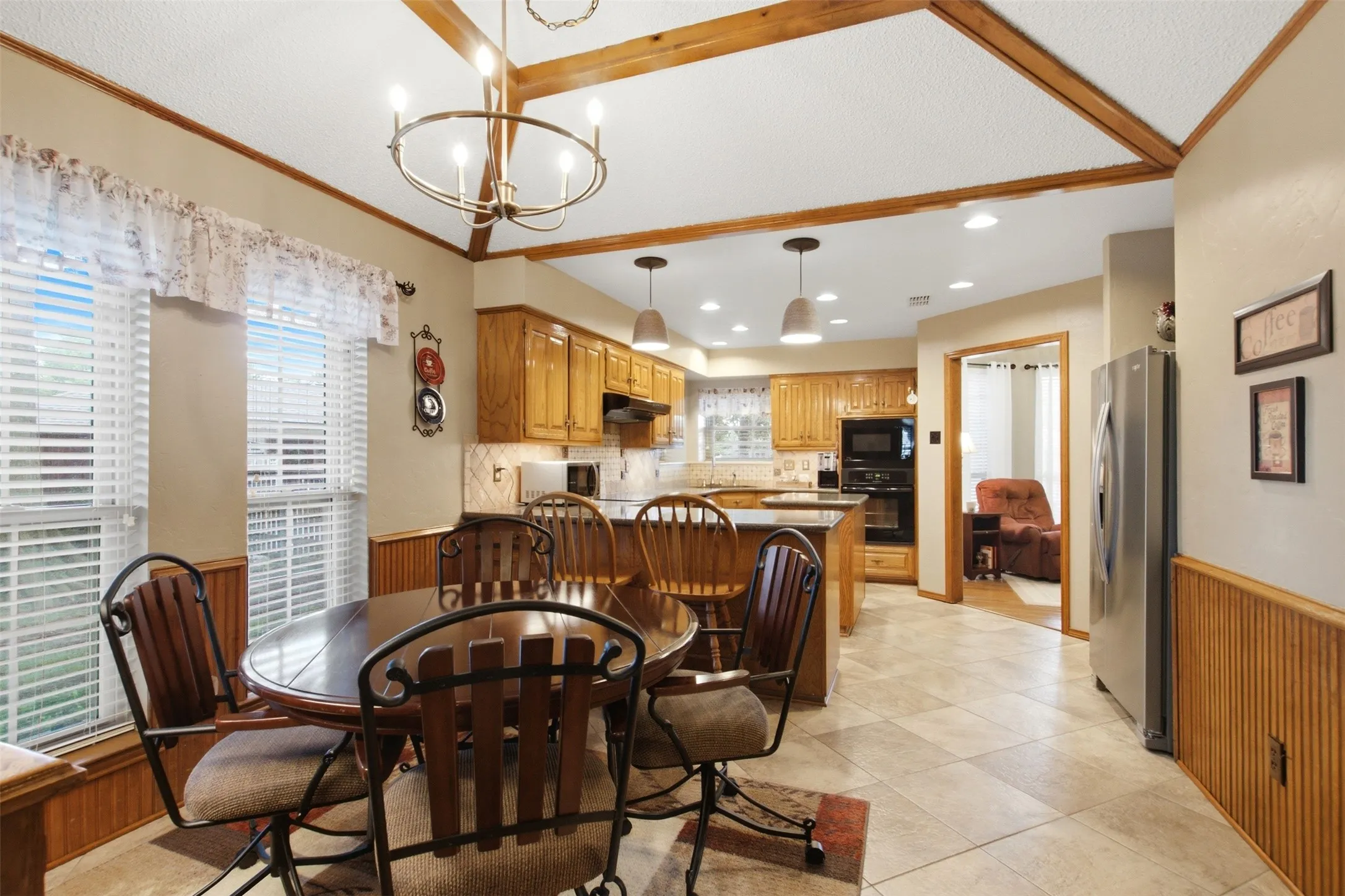 Dining area featuring a circular wood-finish table, wood-finish wainscoting, and a decorative chandelier