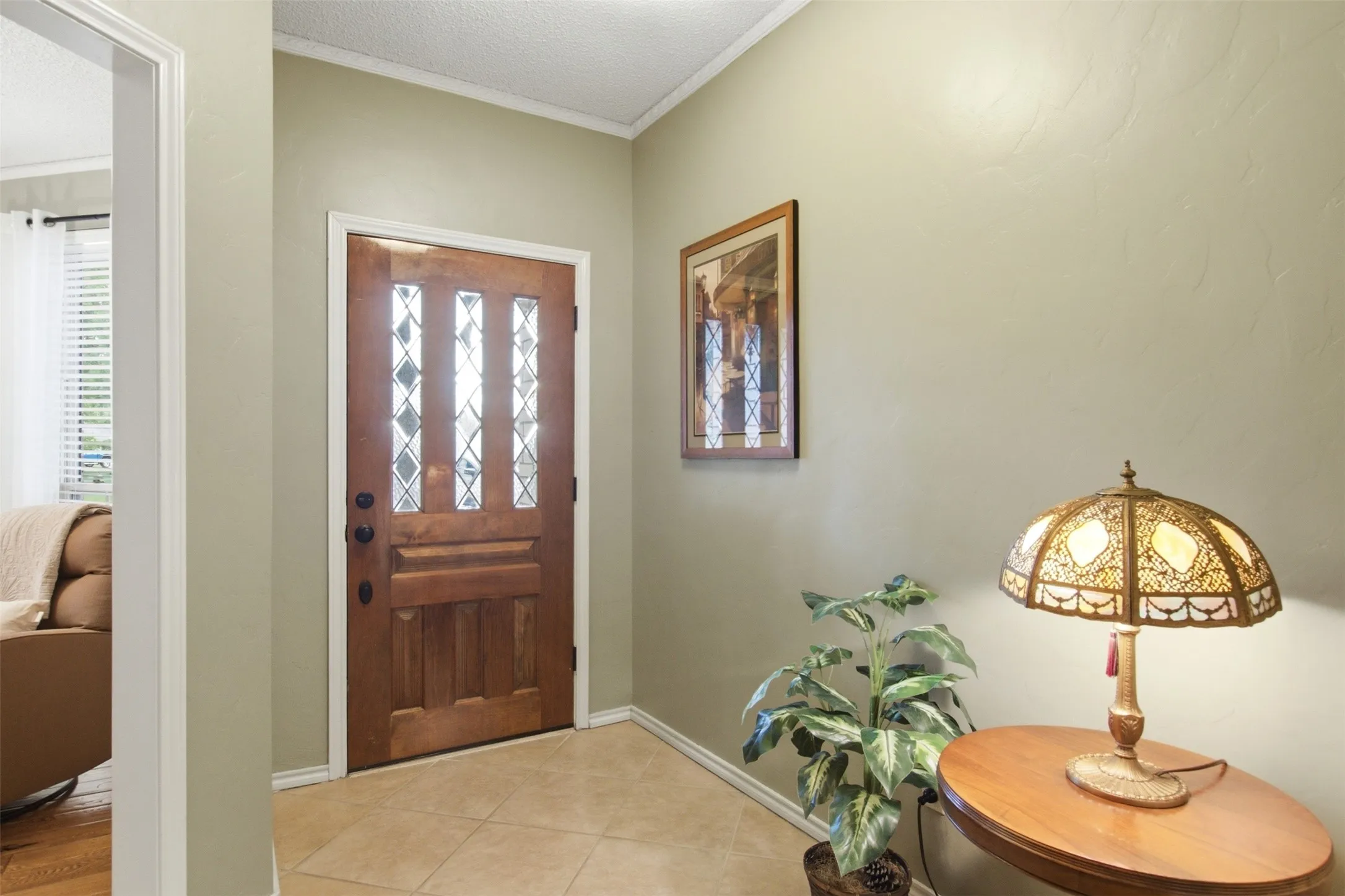 Entryway featuring a wood-panel door with decorative glass inserts, neutral-toned walls, and ceramic tile flooring