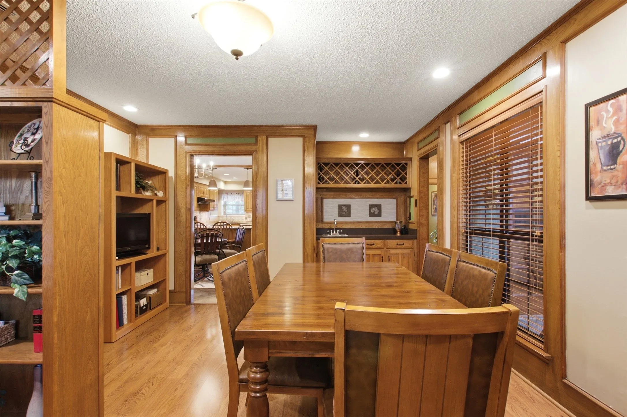 Dining area featuring wood-finish flooring, recessed lighting, and a built-in wet bar with a wine rack